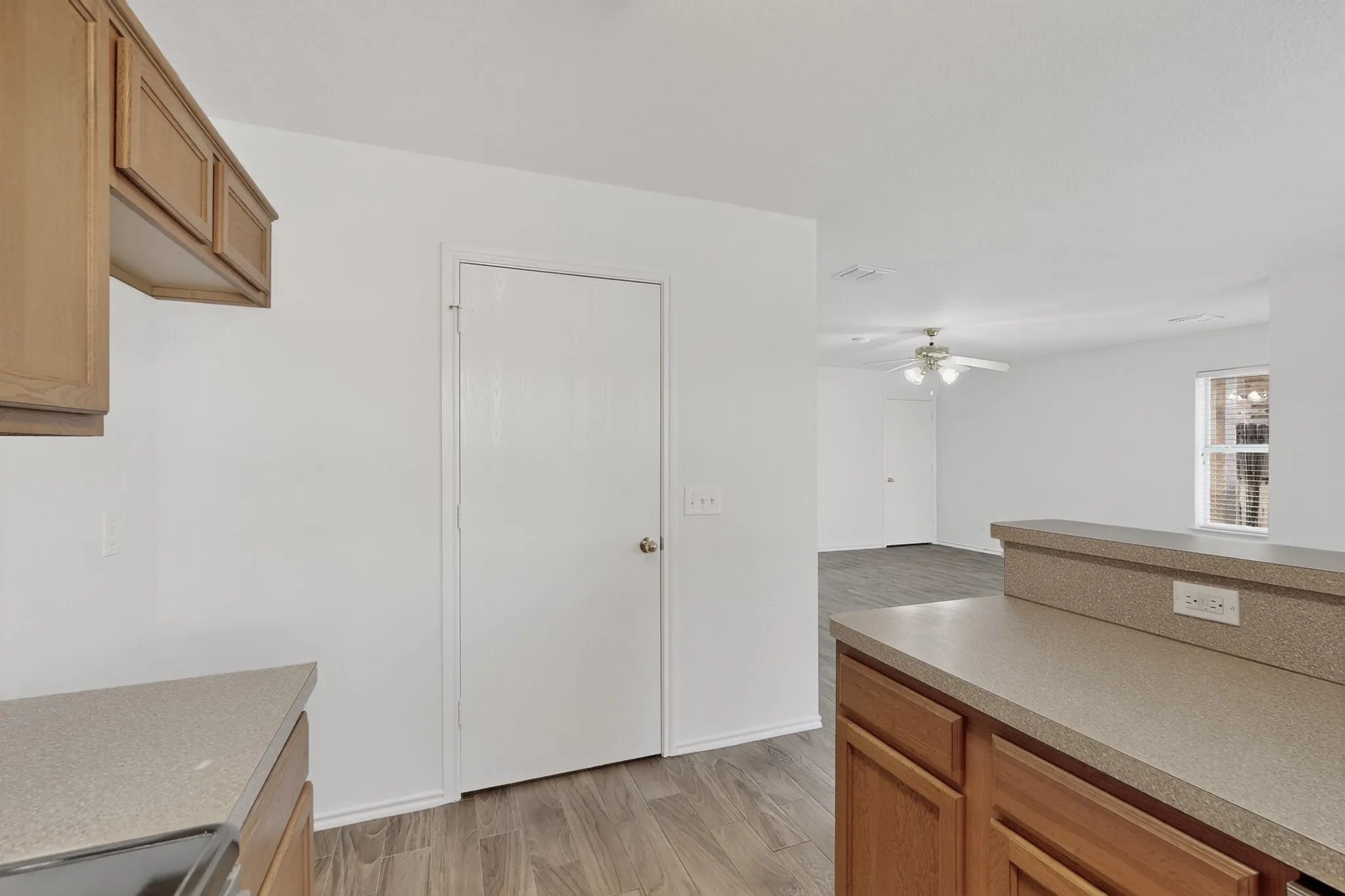 Wood-finish flooring throughout, light-toned cabinetry, and light-colored countertops