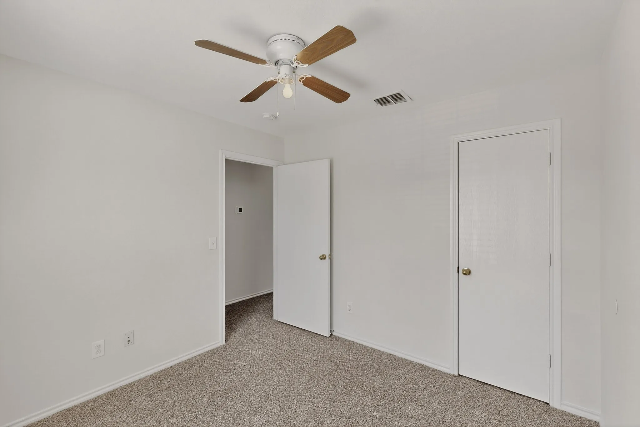 Carpeted flooring with light-colored walls and a ceiling fan