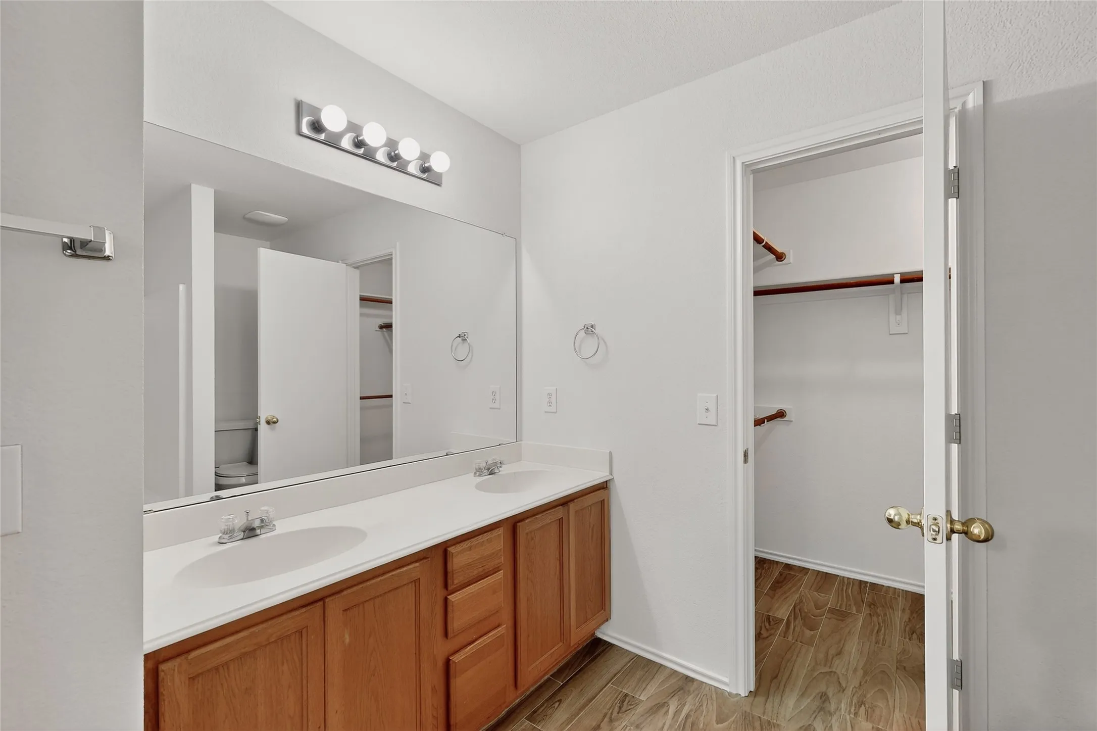 Dual vanity with integrated sinks, wood-finish cabinetry, and a full-width mirror