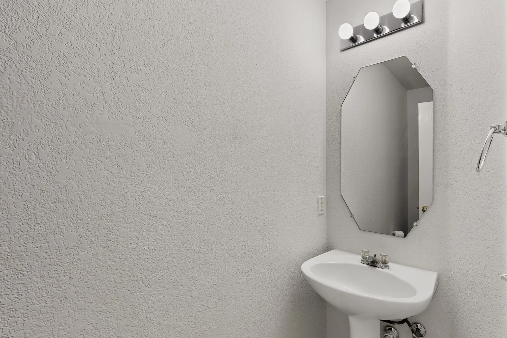 1at Floor Powder Bathroom, Pedestal sink with chrome fixtures, an octagonal mirror, and a four-light vanity fixture