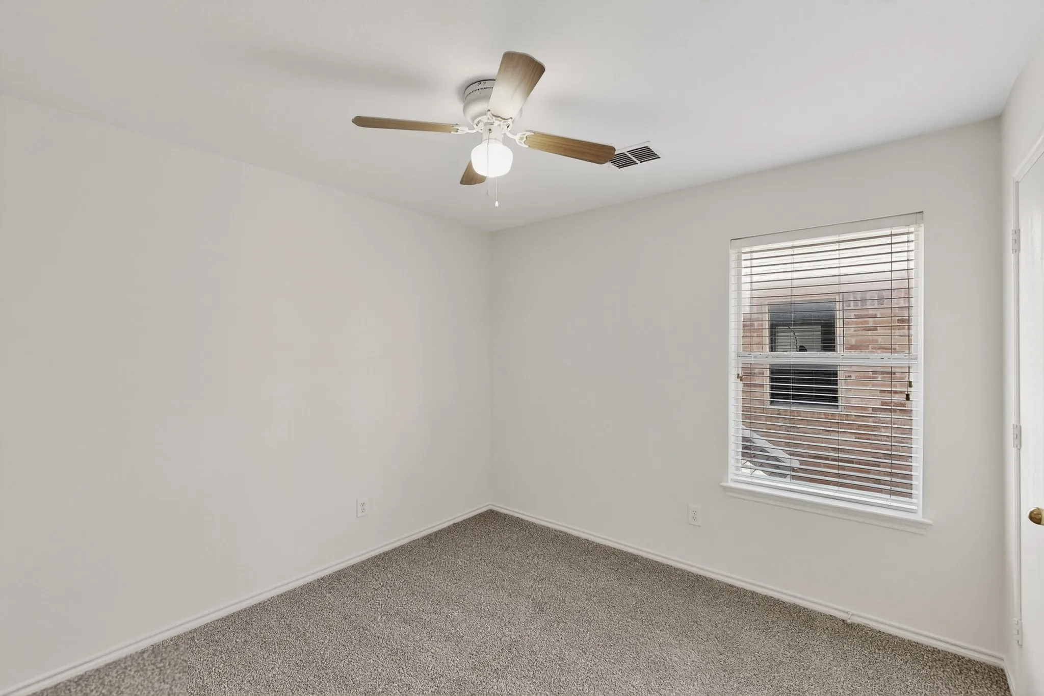 Neutral wall paint, carpet flooring, a ceiling fan with light, and a window with blinds