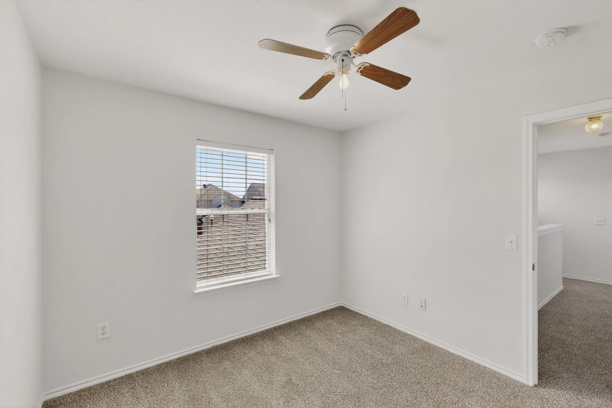 Neutral wall paint, carpet flooring, a ceiling fan with light, and a window with blinds
