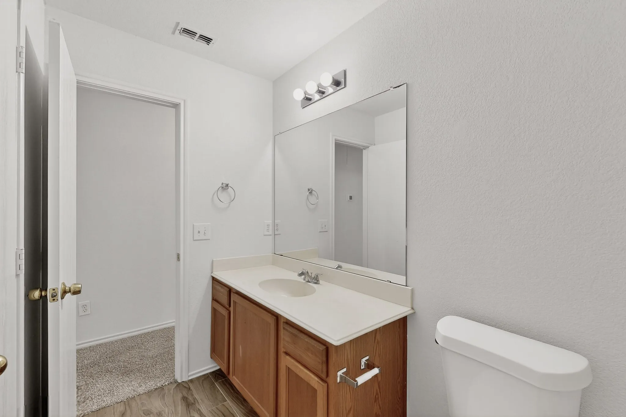 2nd floor Spa-inspired bathroom featuring a wood-finish vanity with dual sink configuration, white quartz countertop, large framed mirror with integrated lighting, and ceramic tile flooring