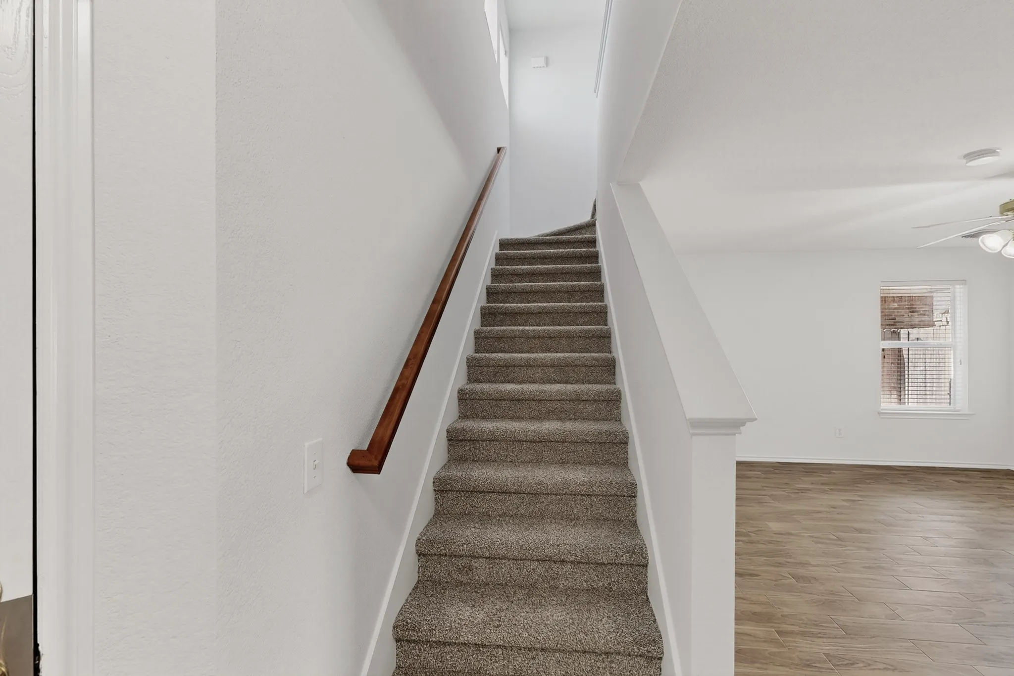 Carpeted staircase with a wood-finish handrail
