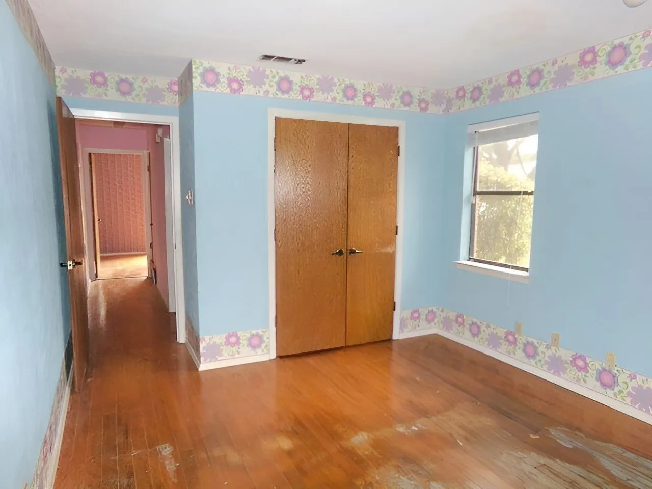 Hardwood-finish flooring, a double-door closet, and a clear window with trim