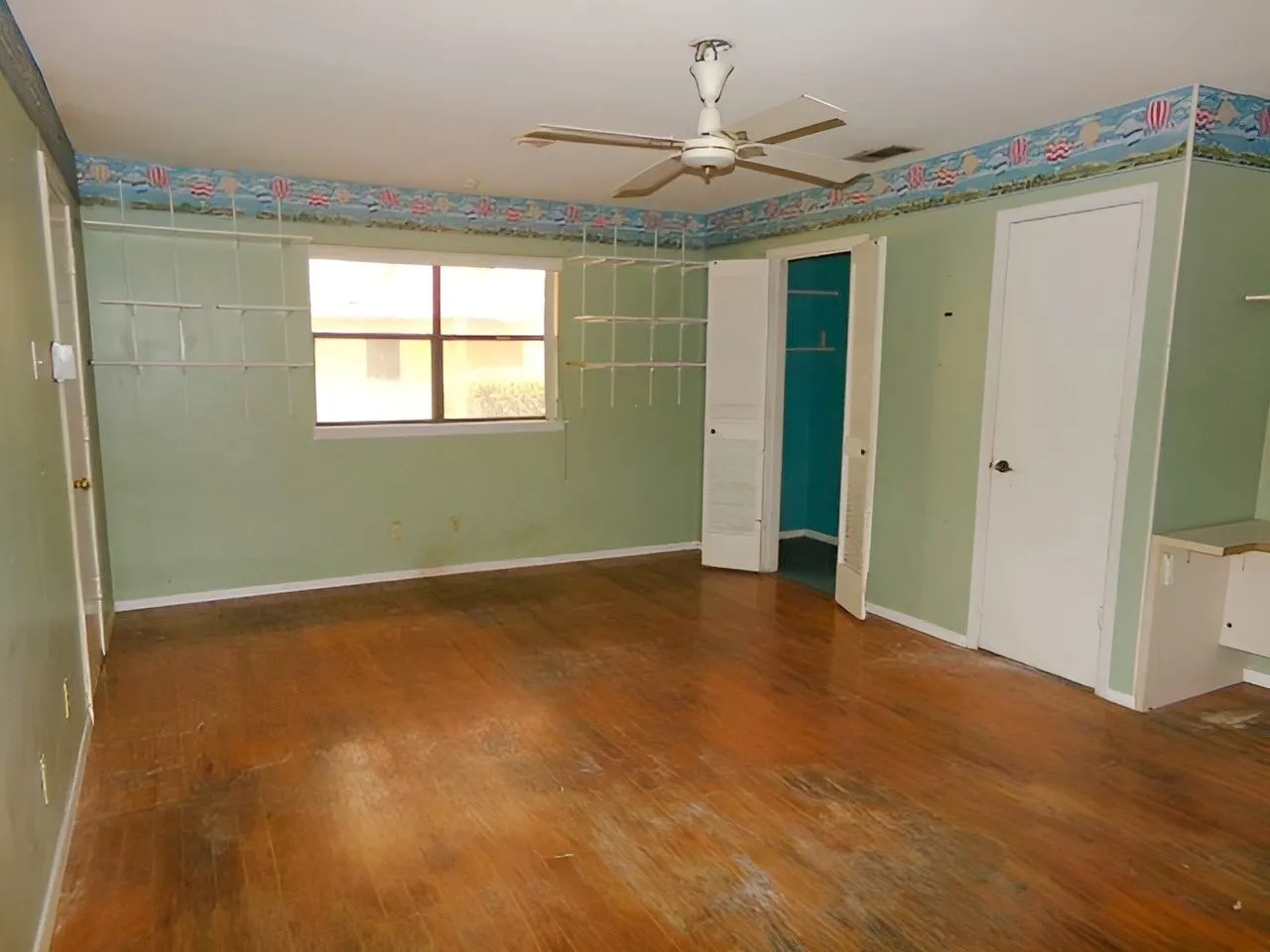 Wood-finish flooring throughout, ceiling fan, built-in shelving, window with exterior exposure, and closet with bifold doors