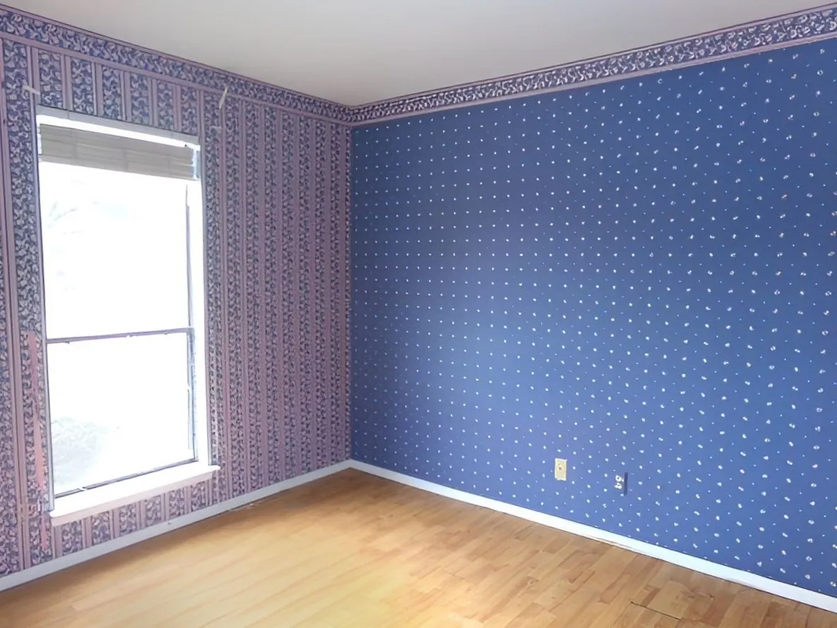 Wood-finish flooring with white trim, double-hung window, and wallpapered walls with decorative border