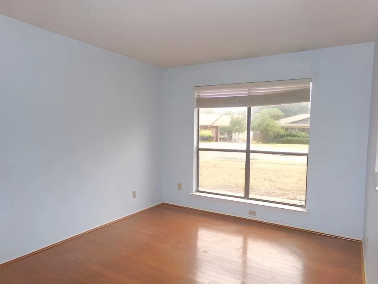 Wood-finish flooring with a neutral wall color, complemented by a large window