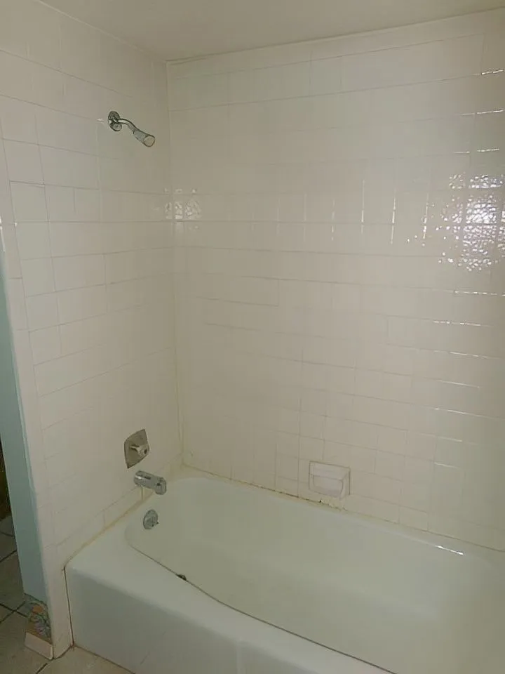 White ceramic tile shower surround with a built-in bathtub