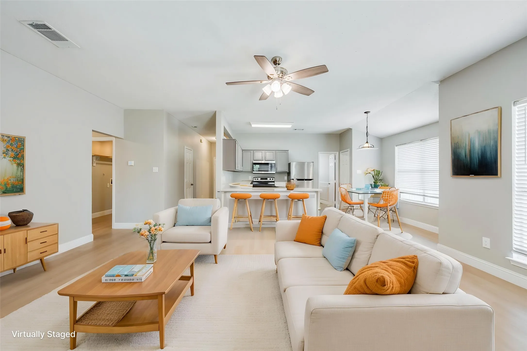 Open-concept living space with wood-finish flooring, a ceiling fan, and multiple windows