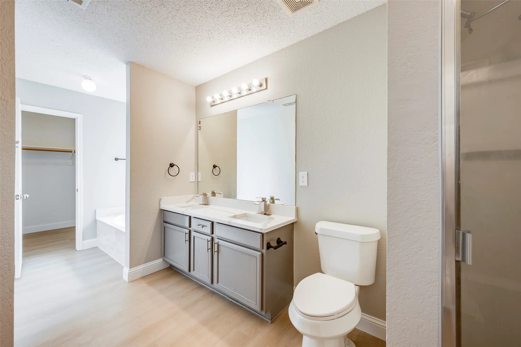 Double vanity with undermount sinks, gray cabinetry, and a full-width mirror