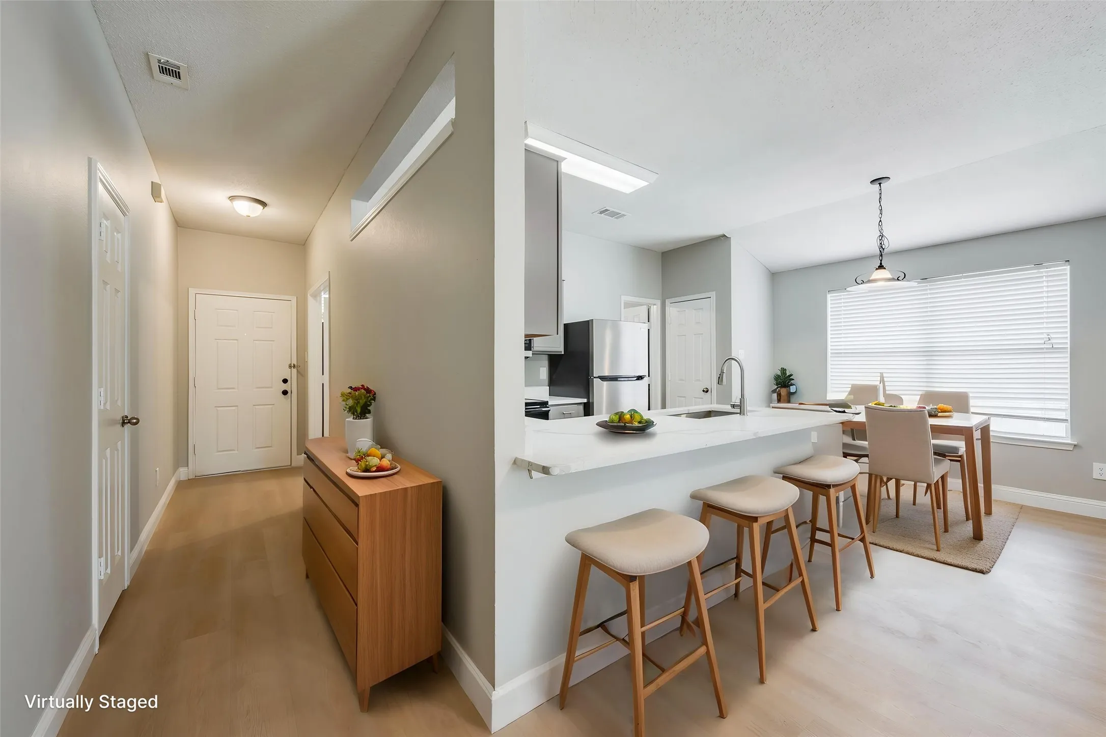 Open-concept kitchen and dining area featuring a breakfast bar, stainless steel refrigerator, and wood-finish flooring