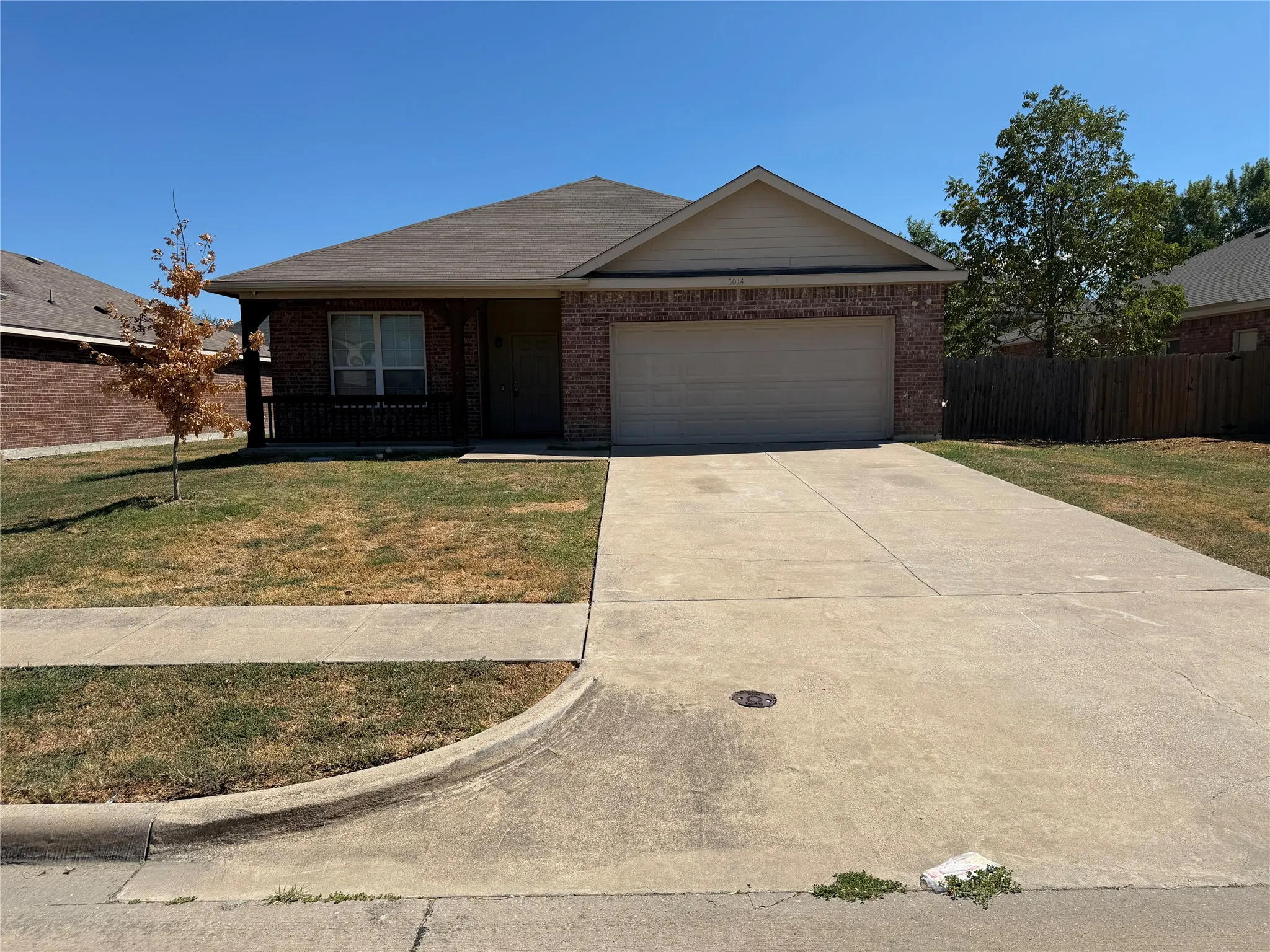 Brick exterior with a covered porch, attached garage, and concrete driveway