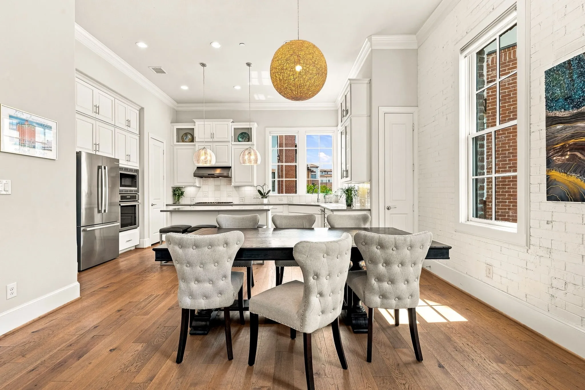 Custom lighting accents, including pendants over the kitchen island and a distinctive dining fixture, add warmth and character.