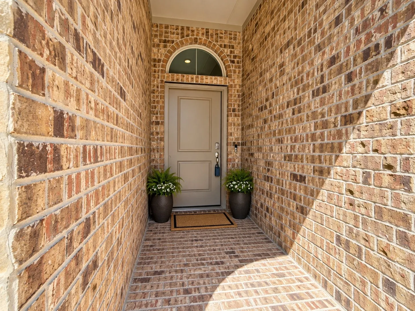 Brick exterior featuring an arched transom window above the entry door
