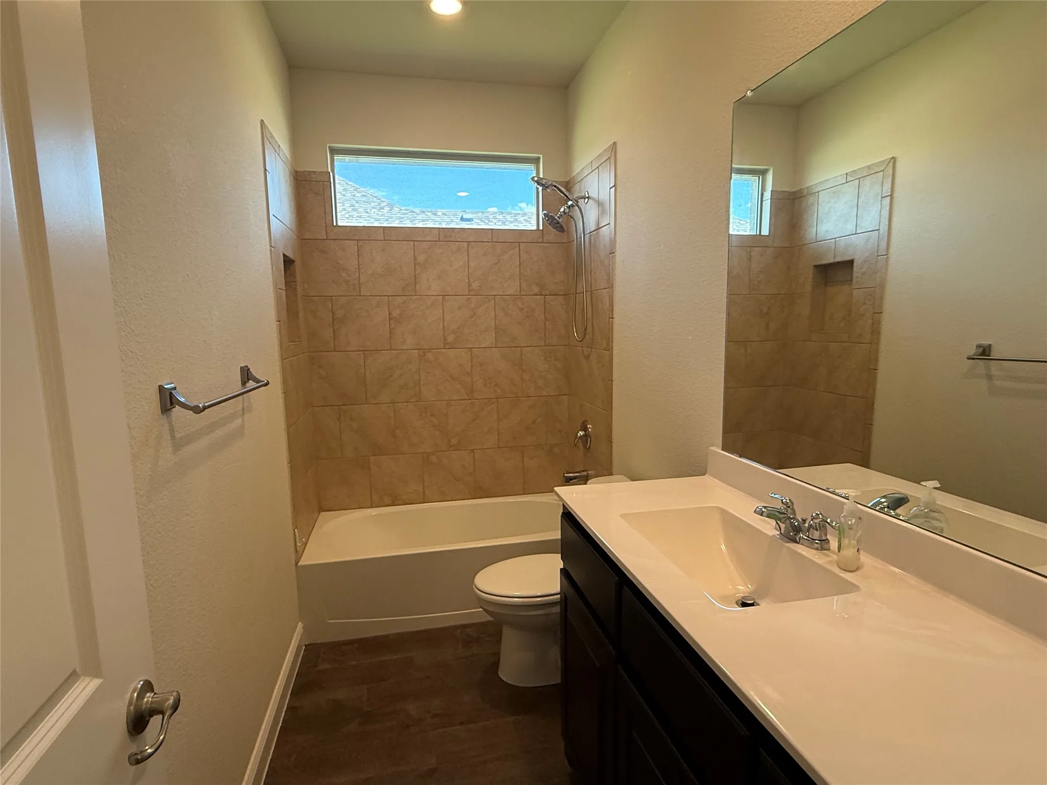 Built-in bathtub with shower, tiled surround, and integrated shower niche