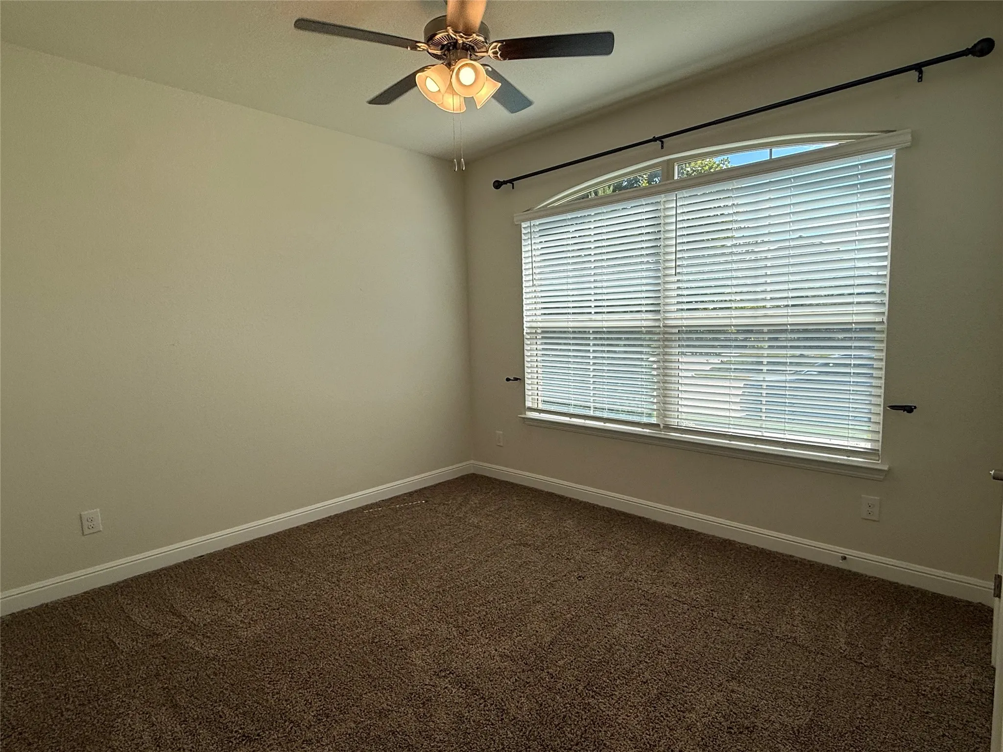Vaulted ceiling featuring a ceiling fan with integrated lighting, a large arched window with blinds, and neutral-toned wall paint