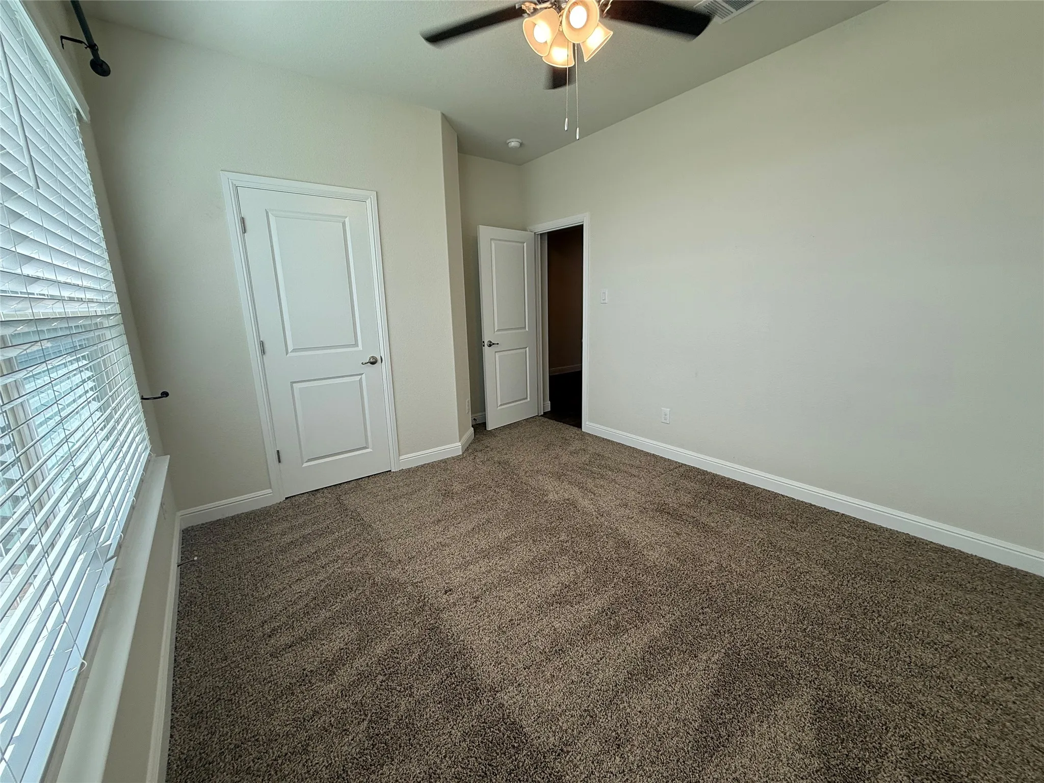 Neutral paint palette with textured carpeting, white trim, and a ceiling fan with integrated lighting