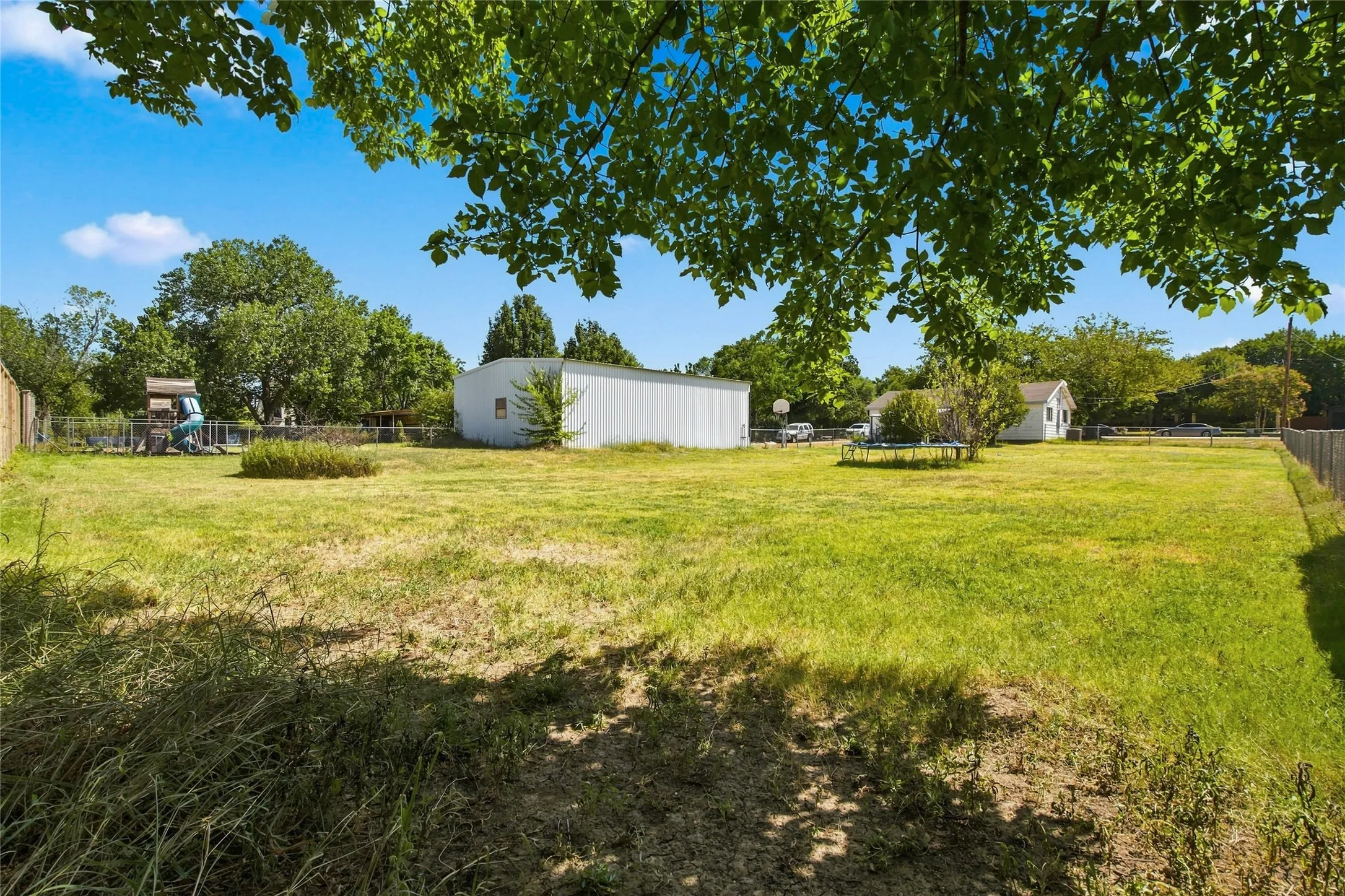 Expansive grassy yard with a privacy fence and mature trees