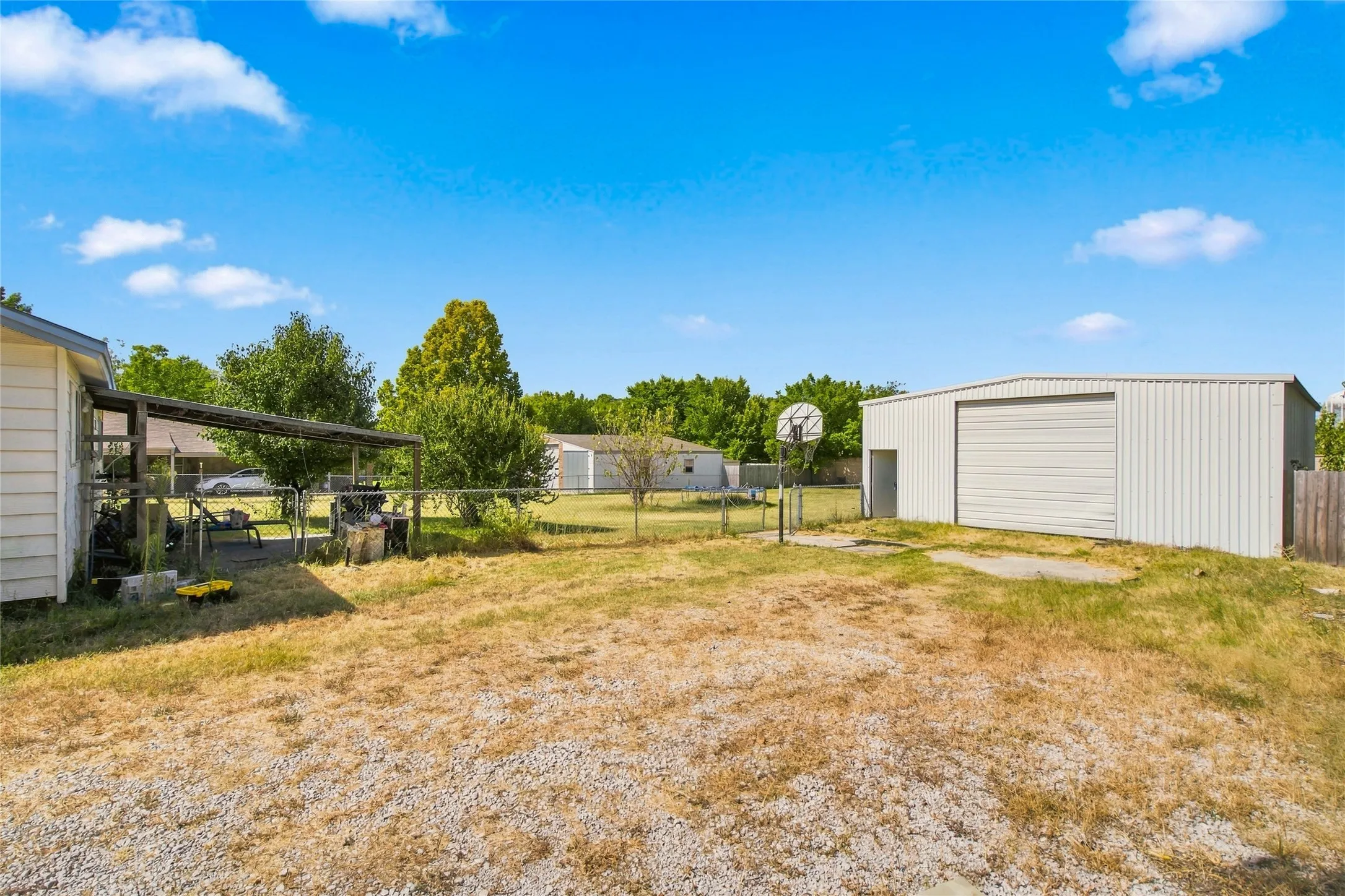 Detached metal building, a covered patio area, and a gravel surface