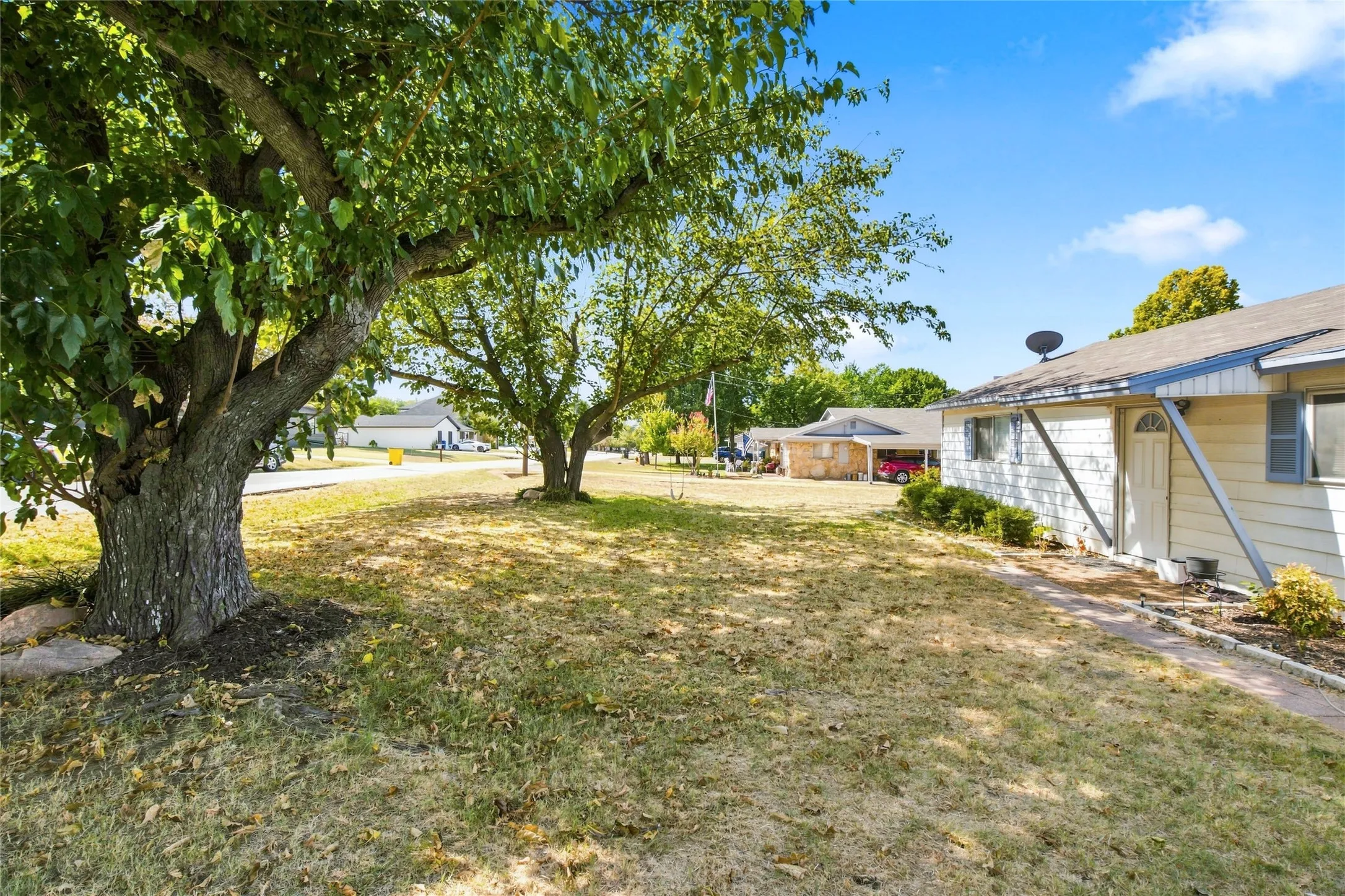 Expansive front yard with mature trees and a paved walkway