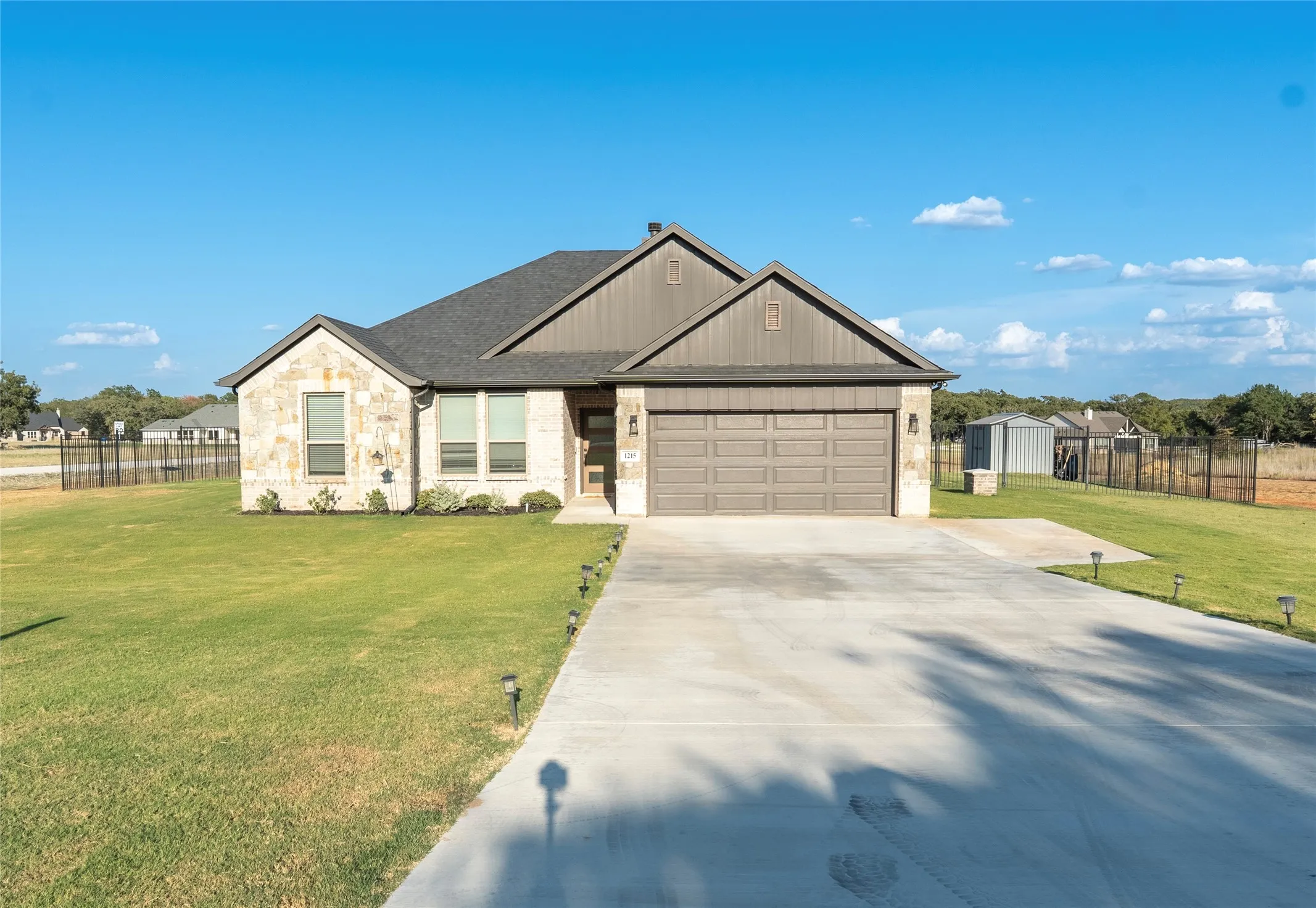 Stone and siding exterior with a two-car garage, concrete driveway, and front yard landscaping