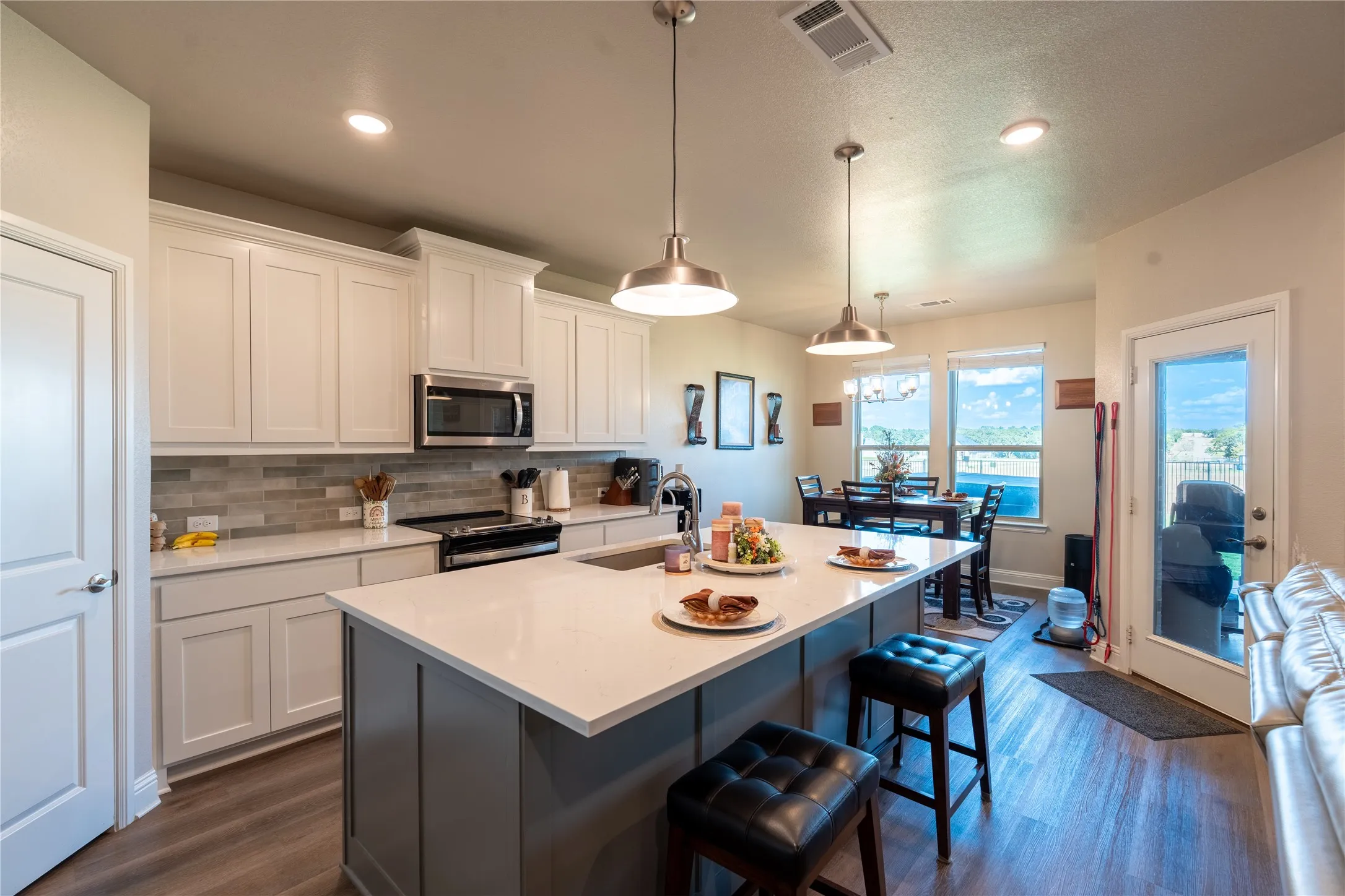 Kitchen featuring a central island, stainless steel appliances, wood-finish flooring, white cabinetry, and recessed lighting