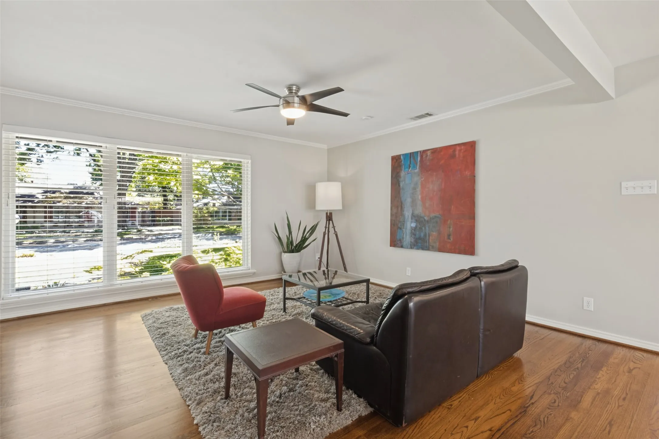 Original Hardwood floors, expansive room featuring wood-finish flooring, large windows with blinds, a ceiling fan with integrated lighting, and crown molding
