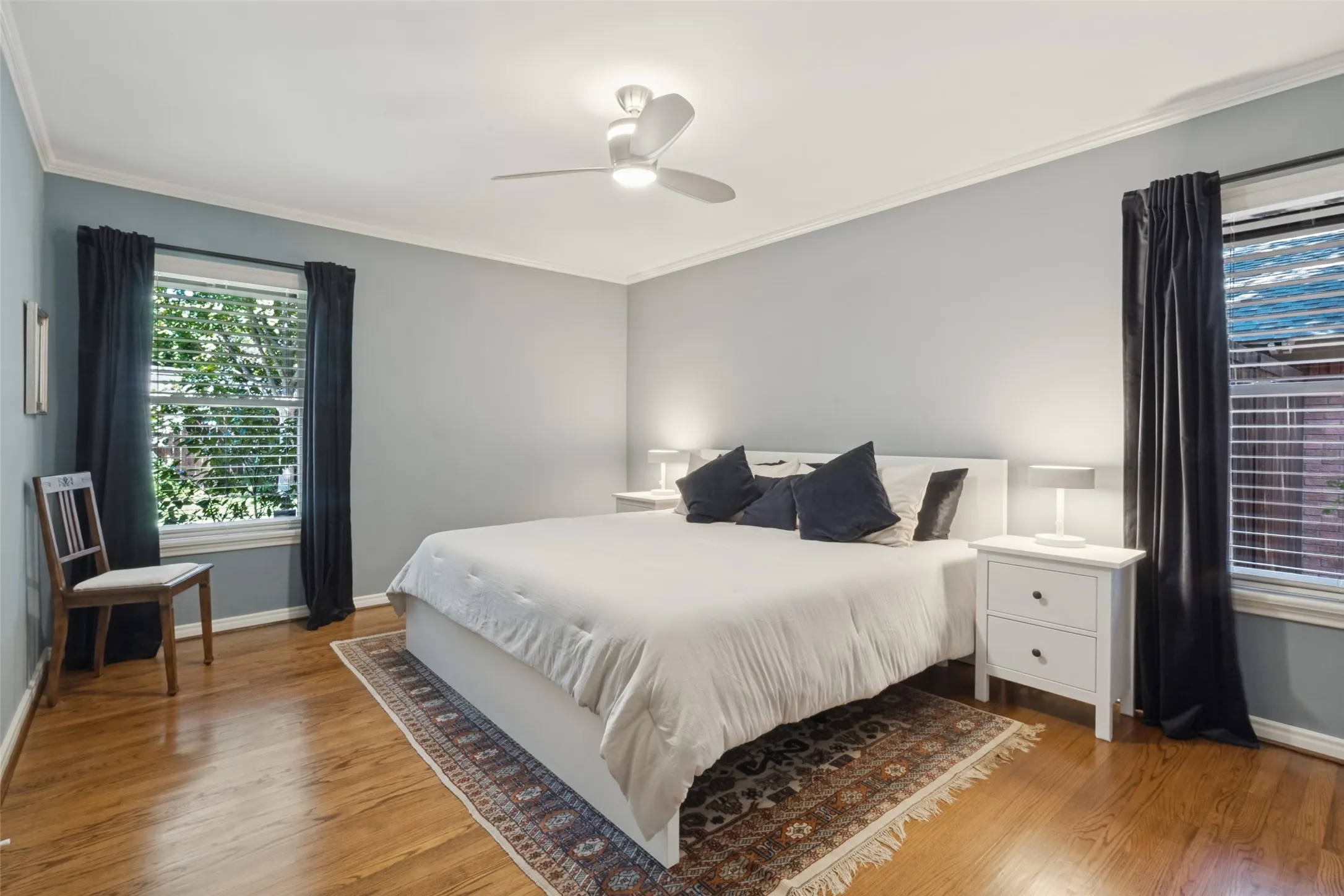 Original Hardwood floors, crown molding, ceiling fan with integrated lighting, and two windows with blinds