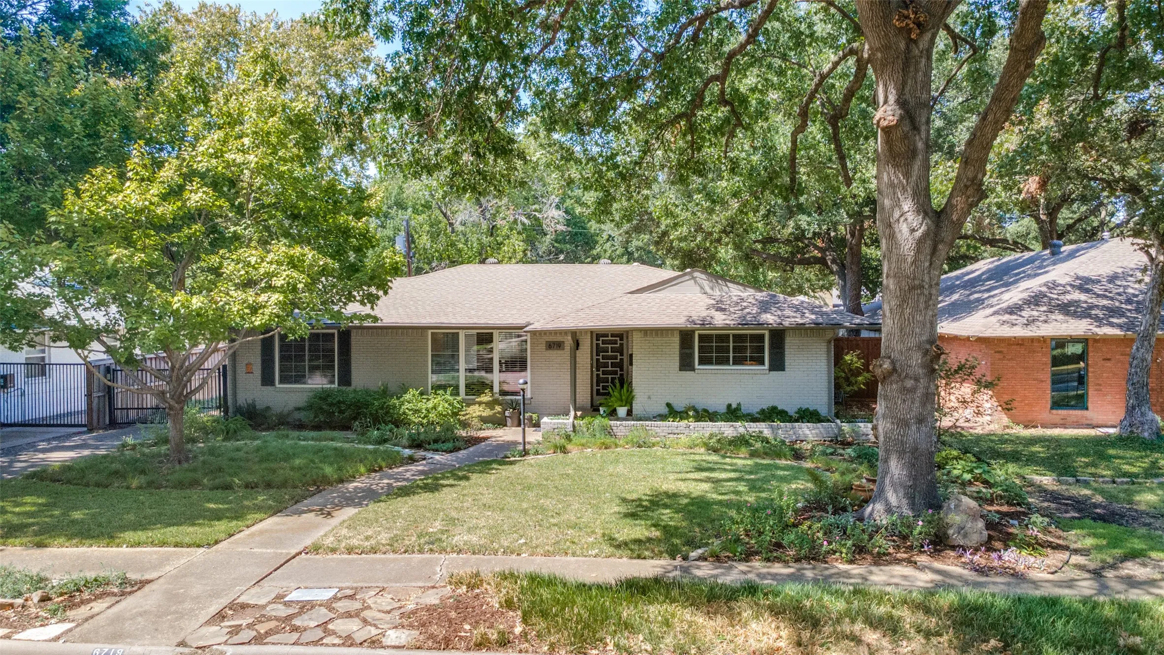 Ranch-style exterior with a light-toned facade, dark window shutters, and a well-maintained lawn