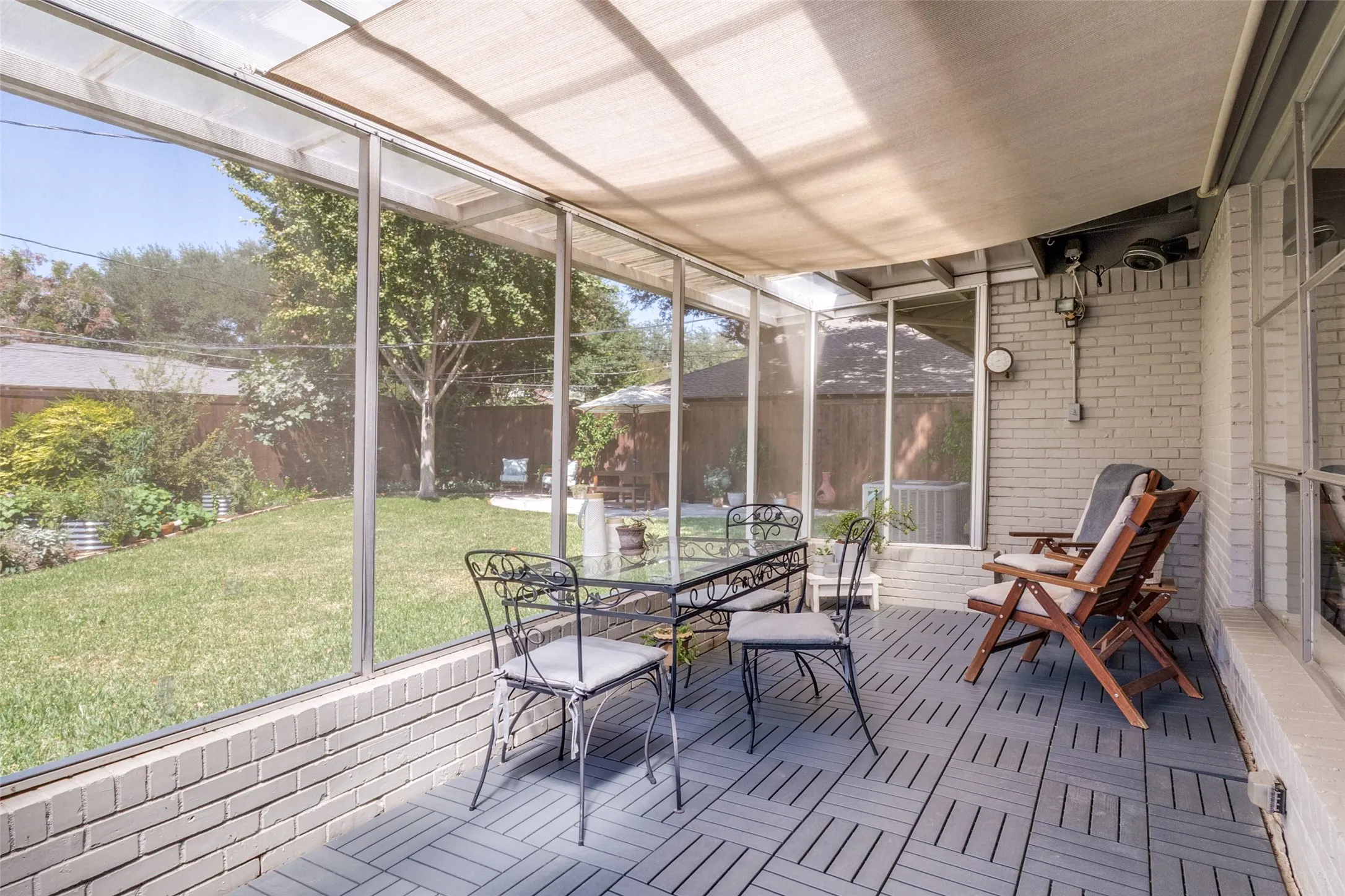 Screened patio featuring a solid roof, brick base, and slatted flooring