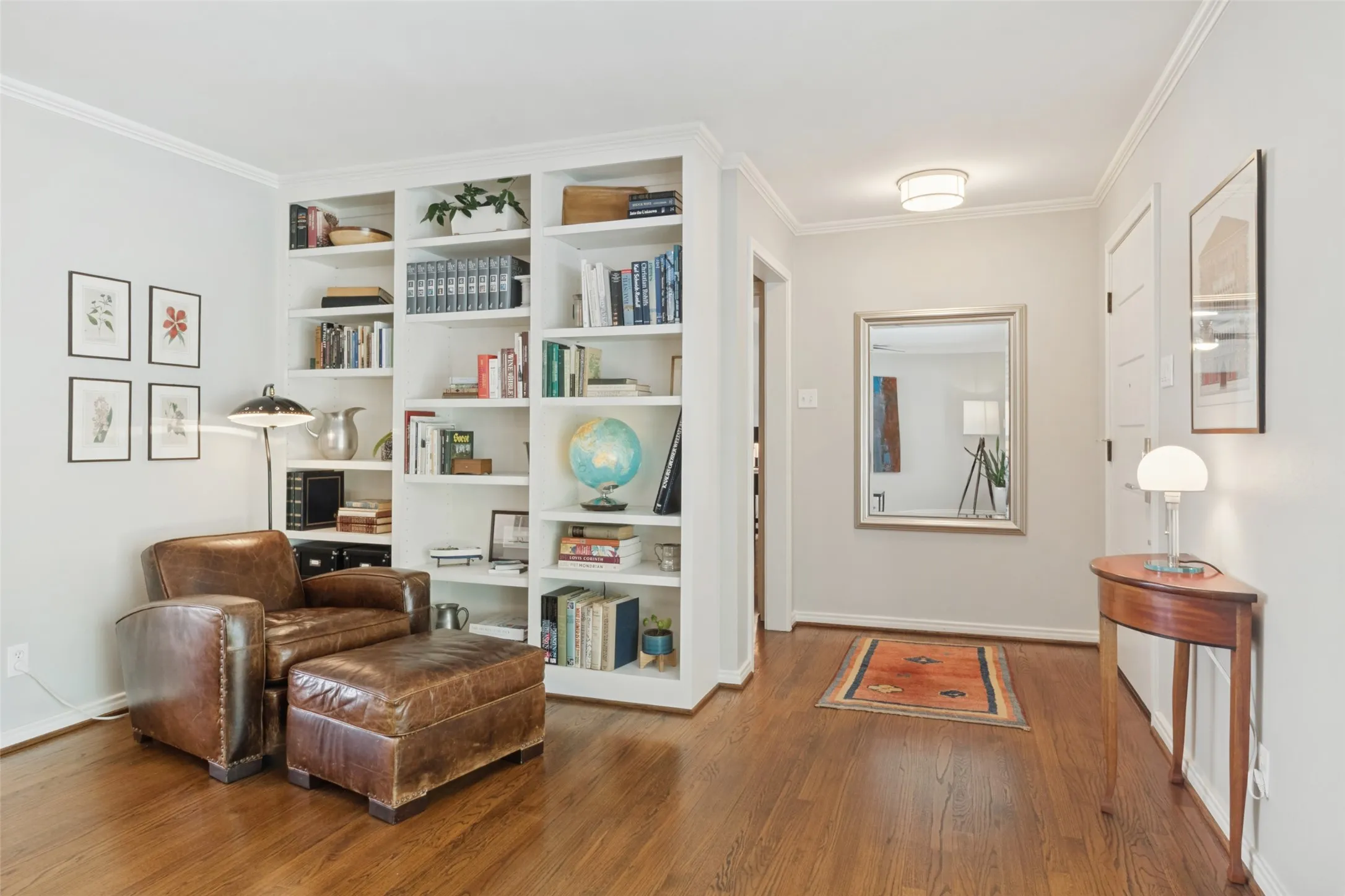 Original Hardwood floors, built-in shelving, crown molding, and a framed mirror