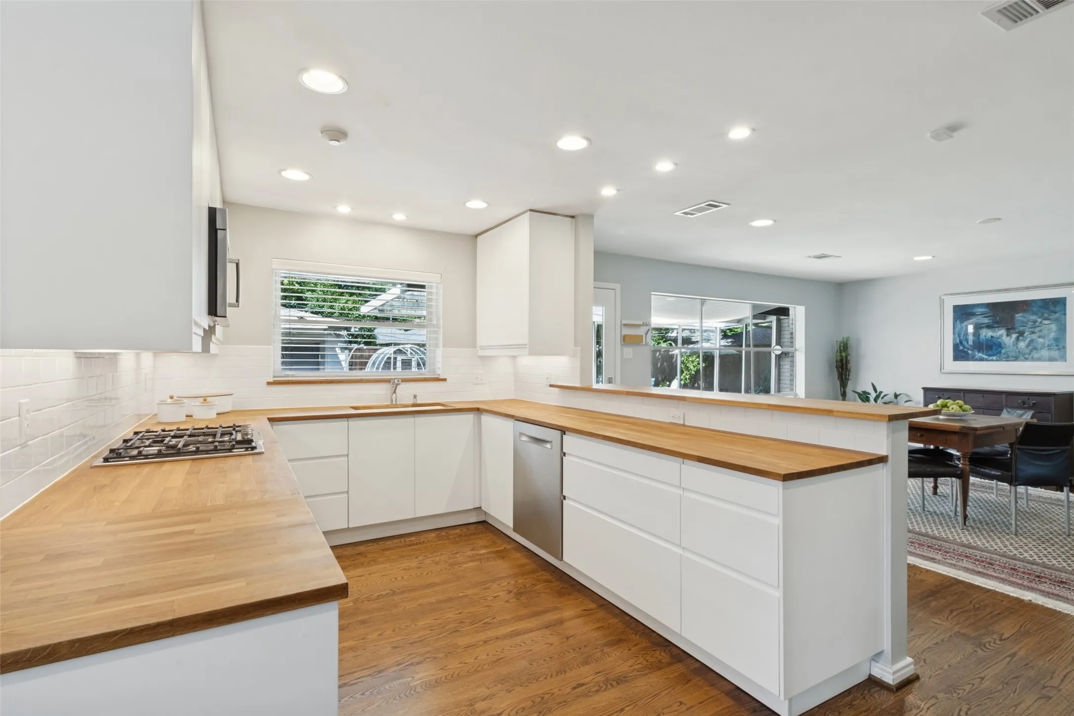 Kitchen featuring wood-finish countertops, white flat-panel cabinetry, a stainless steel dishwasher, a gas cooktop, and recessed lighting