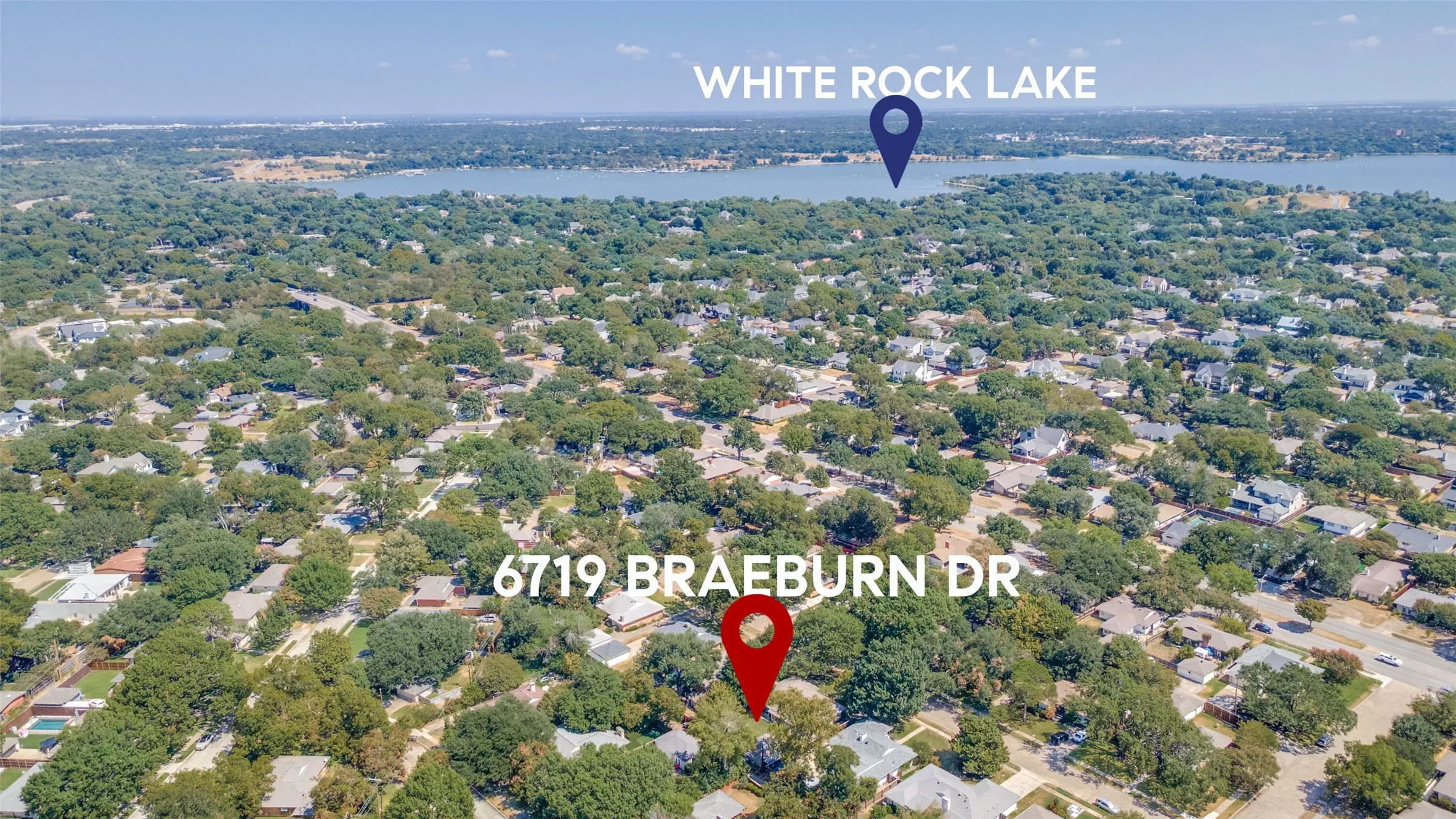Aerial perspective of a tree-lined residential area with a prominent body of water in the background