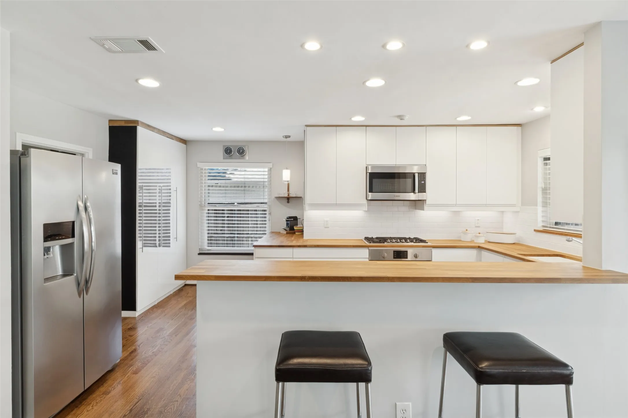 Kitchen featuring white cabinetry, light wood countertops, stainless steel appliances, wood-finish flooring, and recessed lighting
