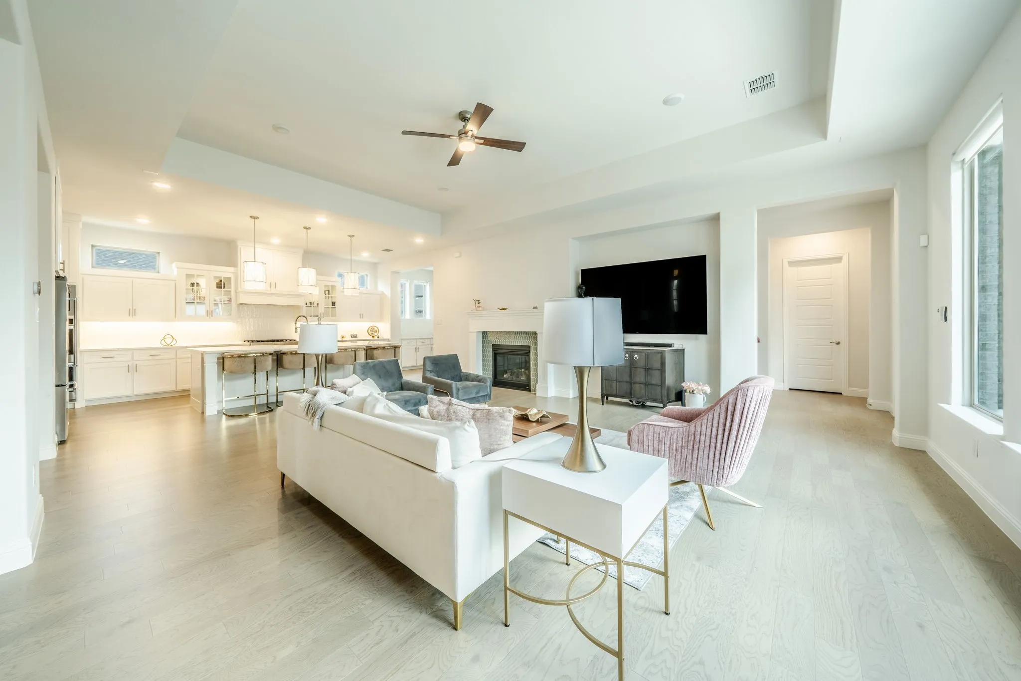 Open-concept living area featuring wood-finish flooring, a contemporary fireplace, recessed lighting, and a ceiling fan
