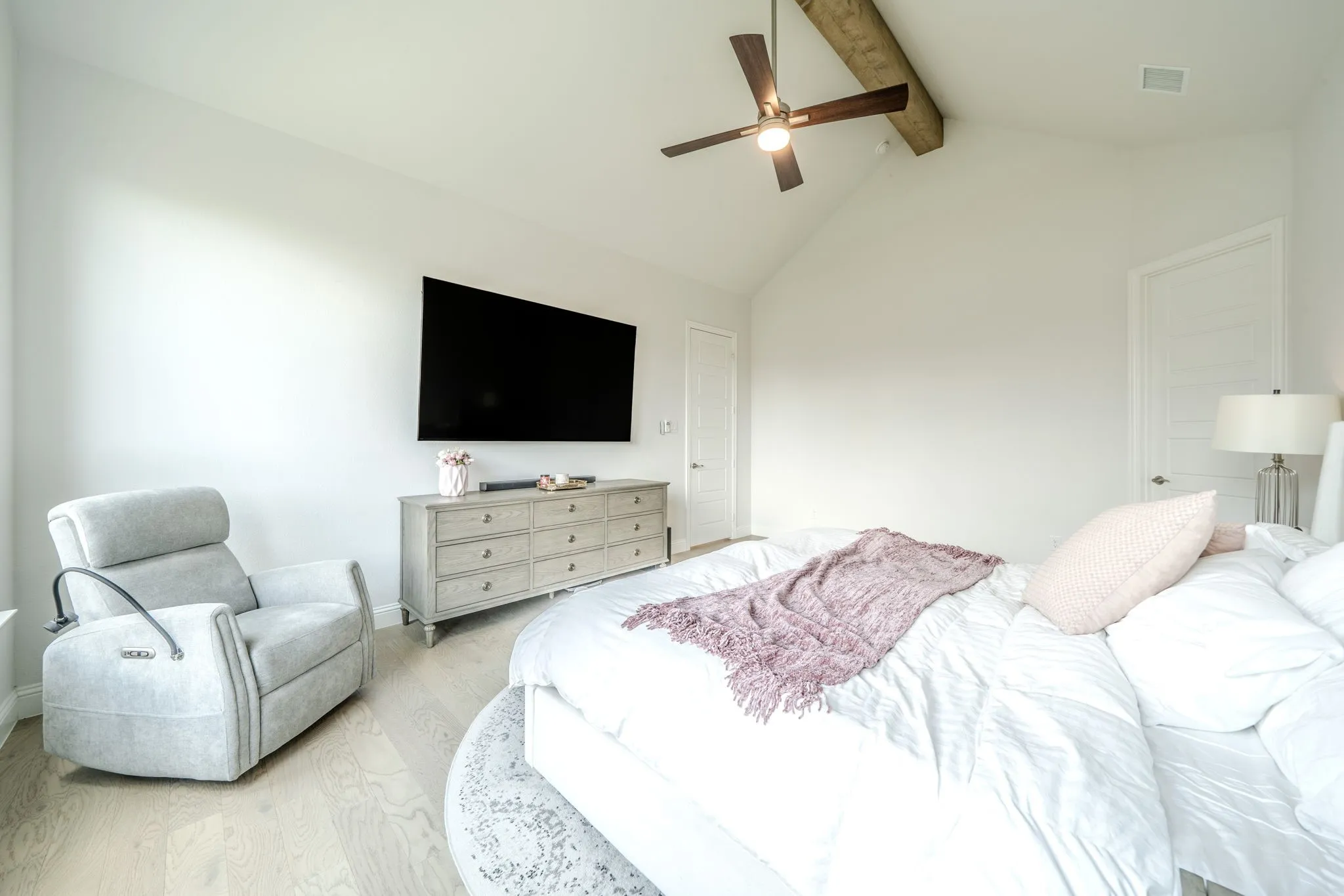 Vaulted ceiling with an exposed wood beam, ceiling fan, wood-finish flooring, and paneled doors