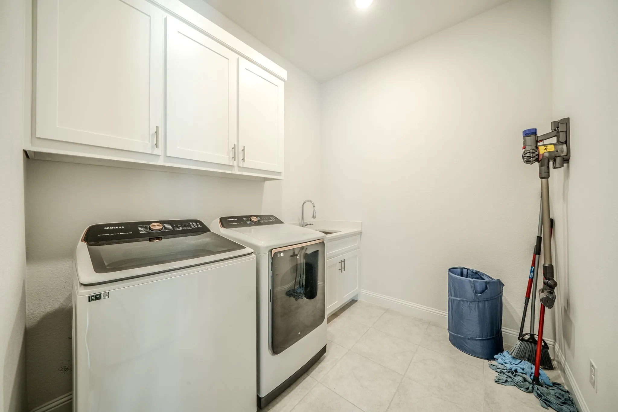 White shaker-style cabinetry with silver hardware, recessed lighting, countertop space, and a stainless steel sink