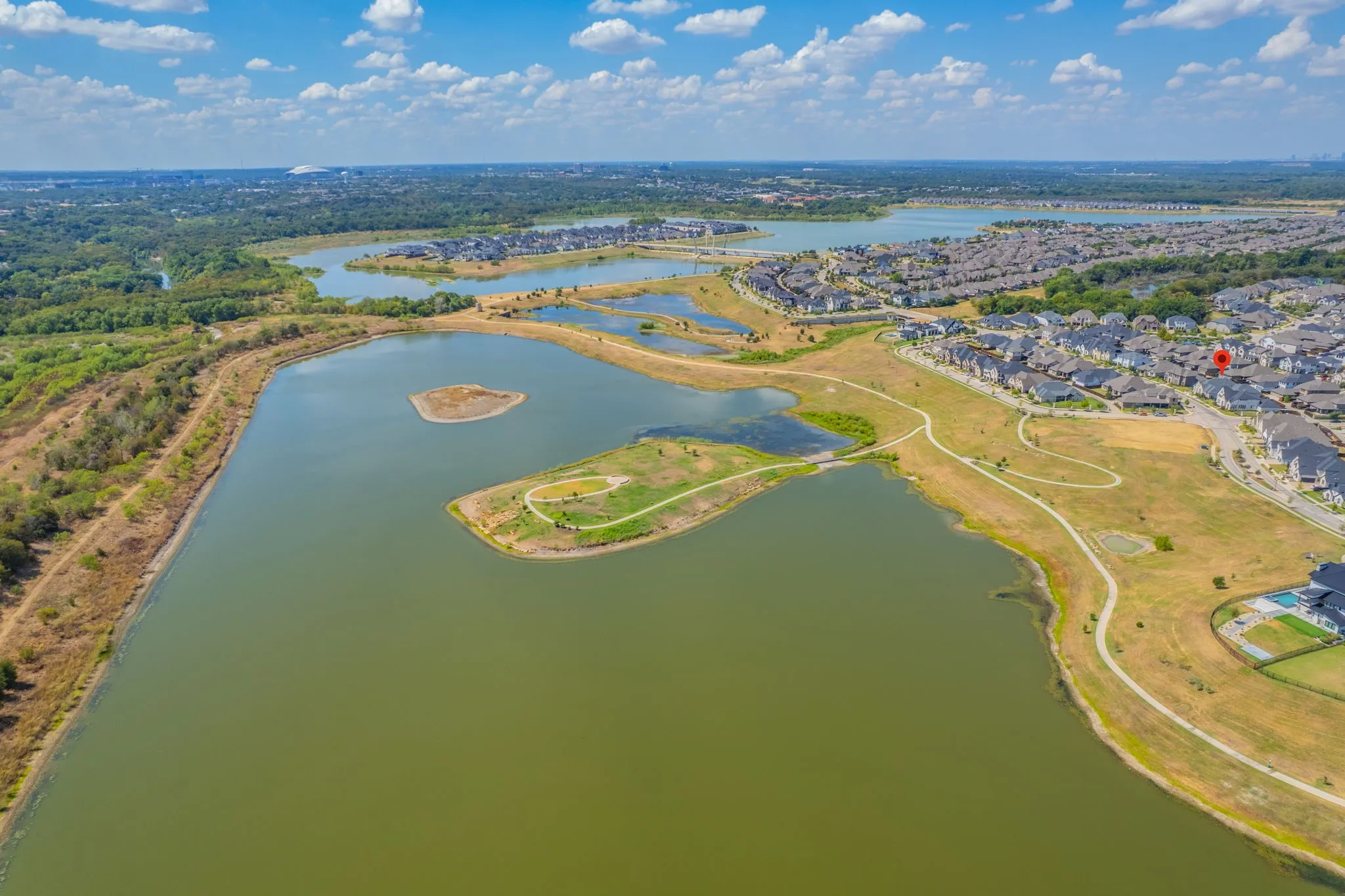 Aerial perspective showcasing a residential development with numerous homes, surrounded by multiple bodies of water