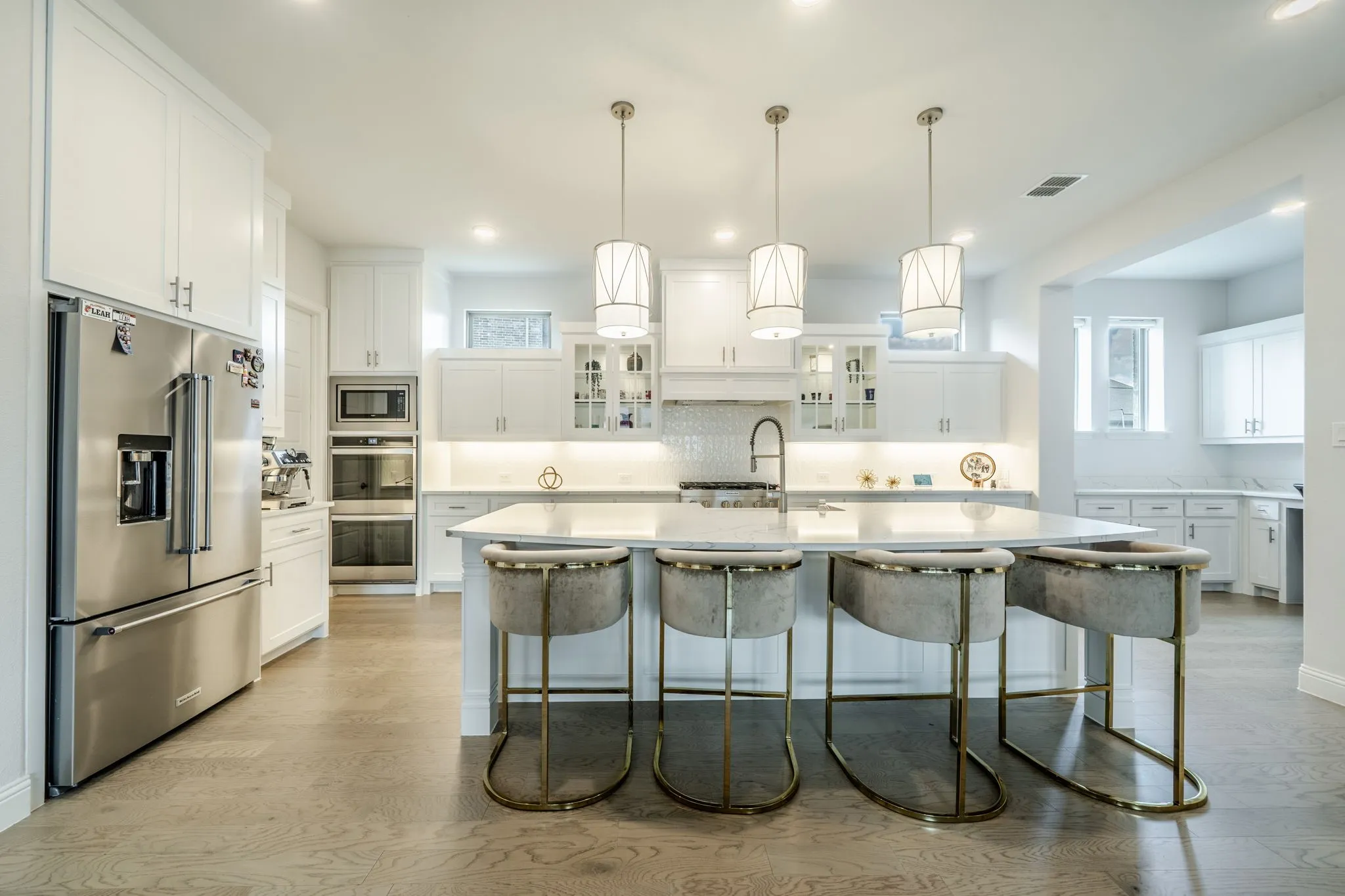 Gourmet kitchen featuring white cabinetry, stainless steel appliances, a large central island, and wood-finish flooring