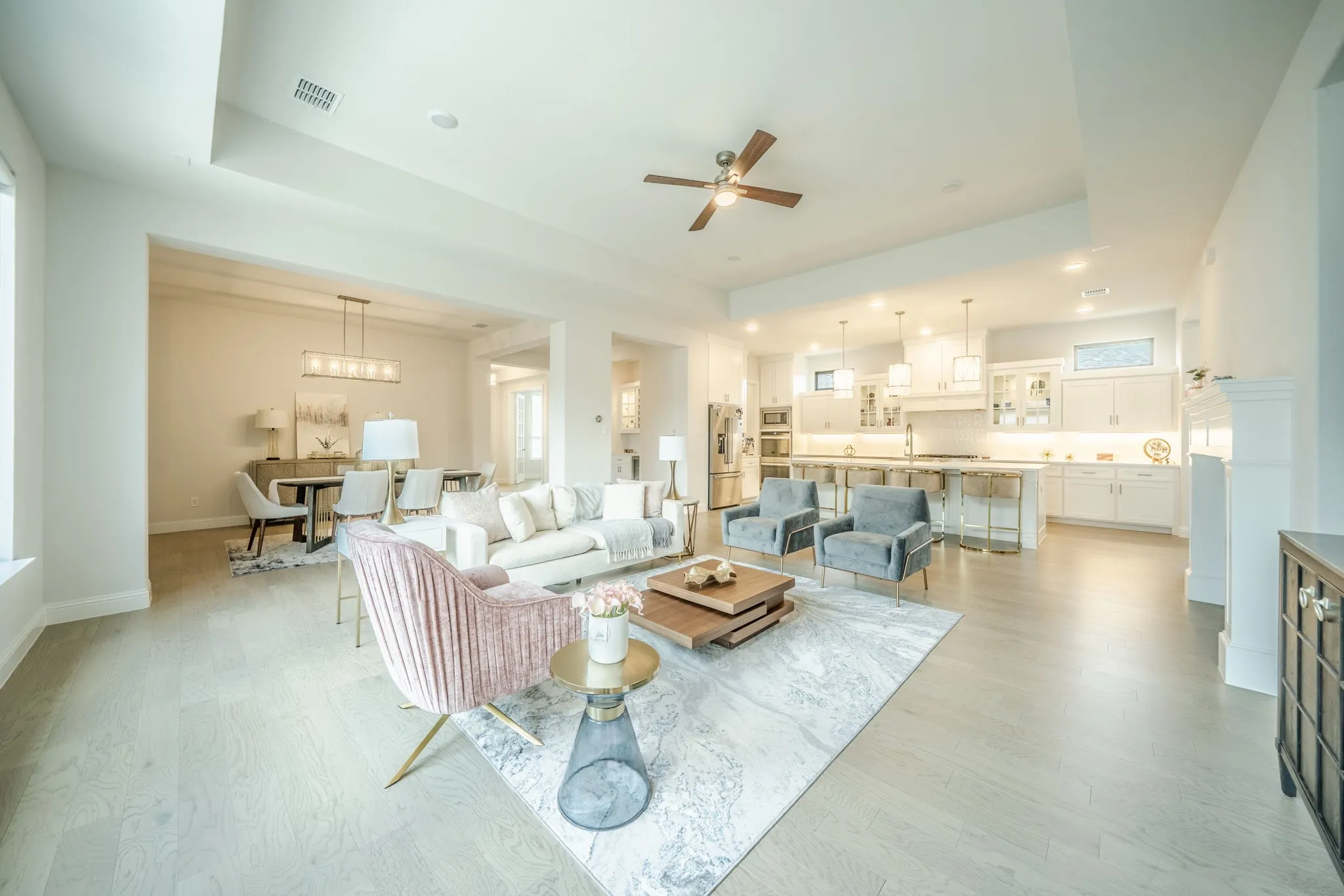 Open-concept living space featuring light wood-finish flooring throughout, recessed ceiling lighting, and a ceiling fan