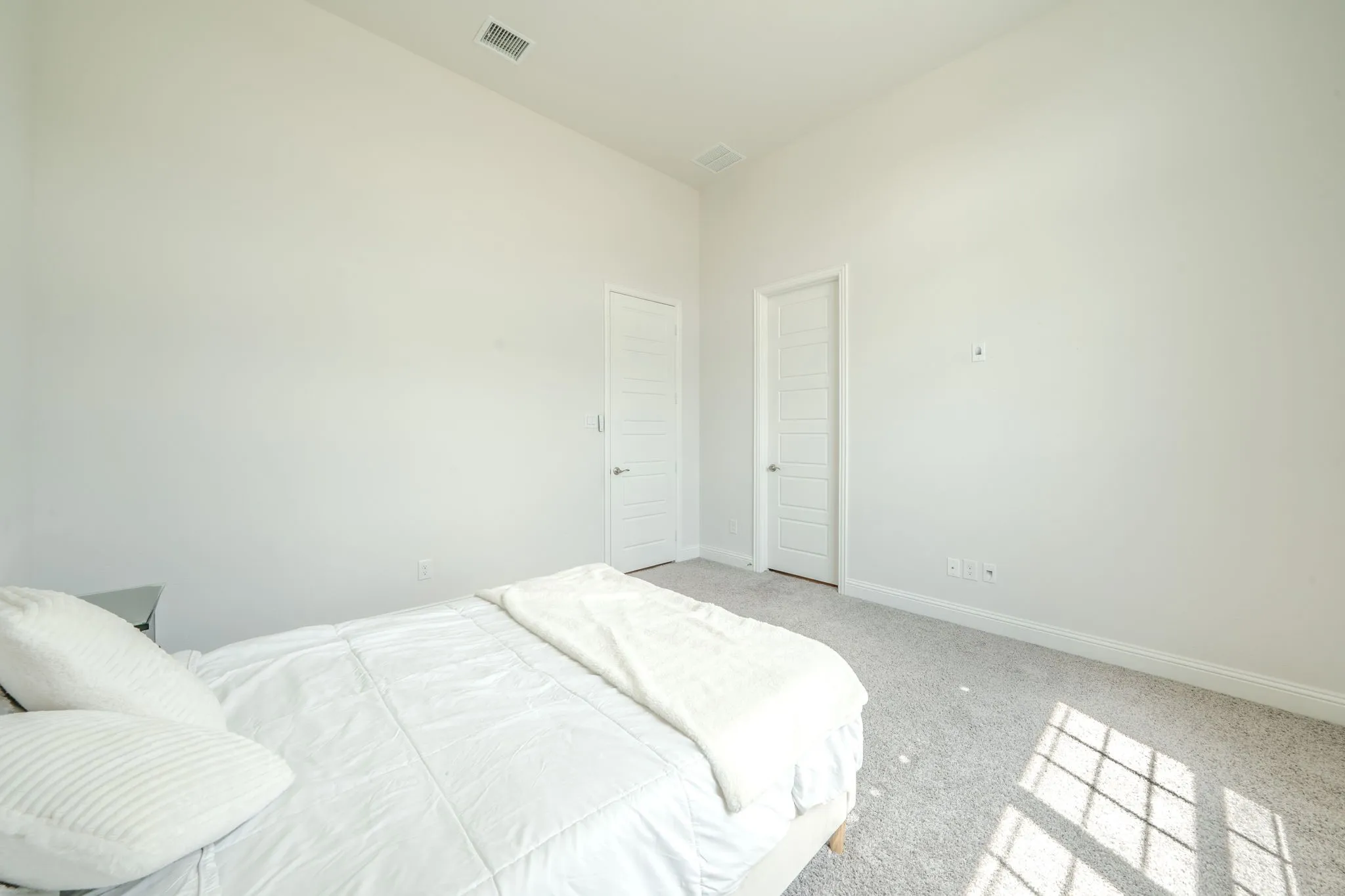 Carpeted flooring, vaulted ceiling, and two white paneled doors