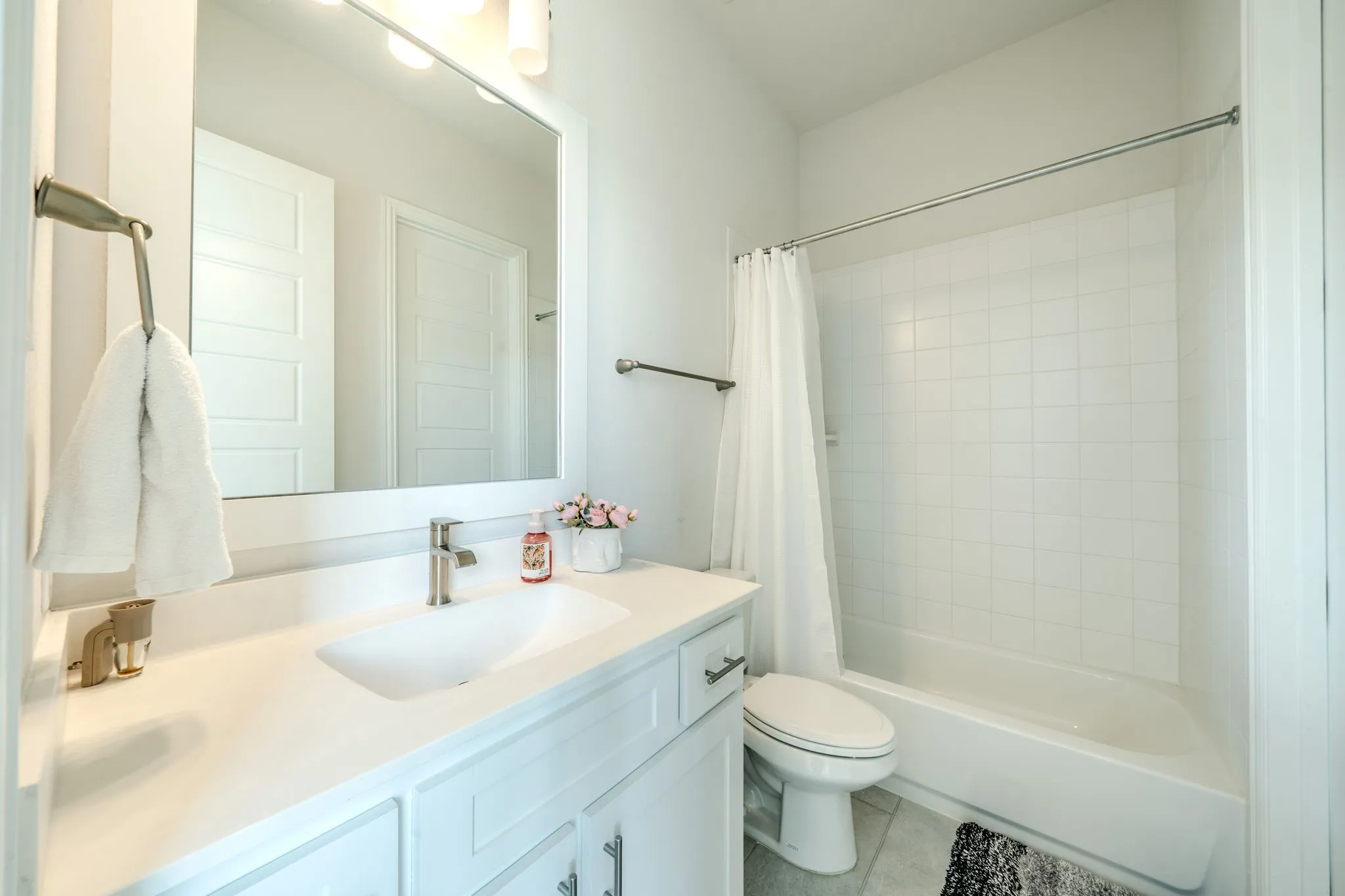Bathroom featuring a single vanity with an undermount sink, a framed mirror, a tub-shower combination with subway tile surround, and brushed nickel fixtures