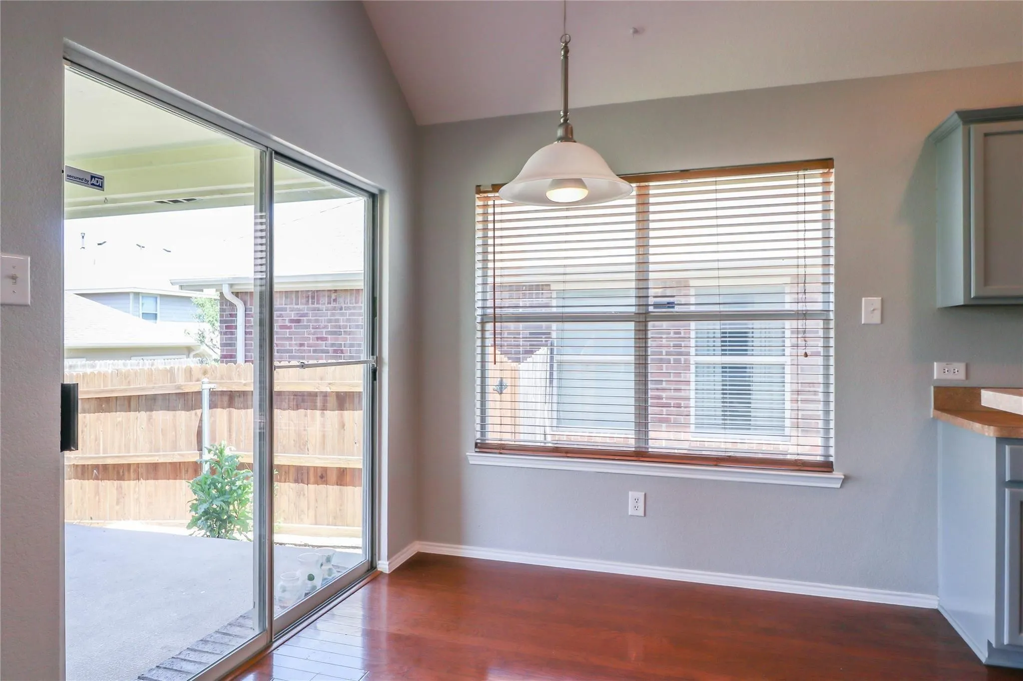 Wood-finish flooring, sliding glass door, pendant light fixture, window with blinds, and built-in cabinetry