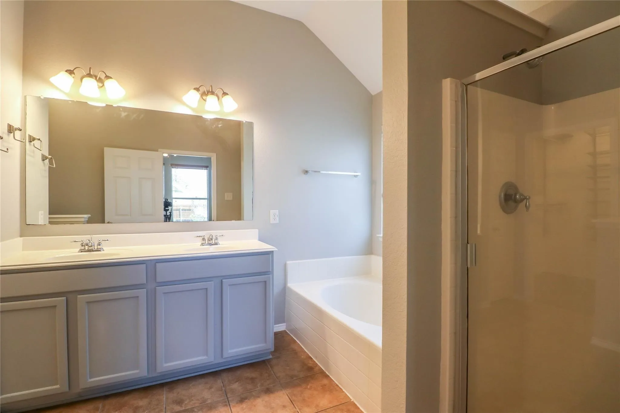 Dual vanity with undermount sinks, large wall mirror, built-in bathtub, and enclosed shower