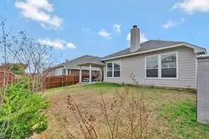 Expansive backyard featuring a covered patio, privacy fencing, and a chimney