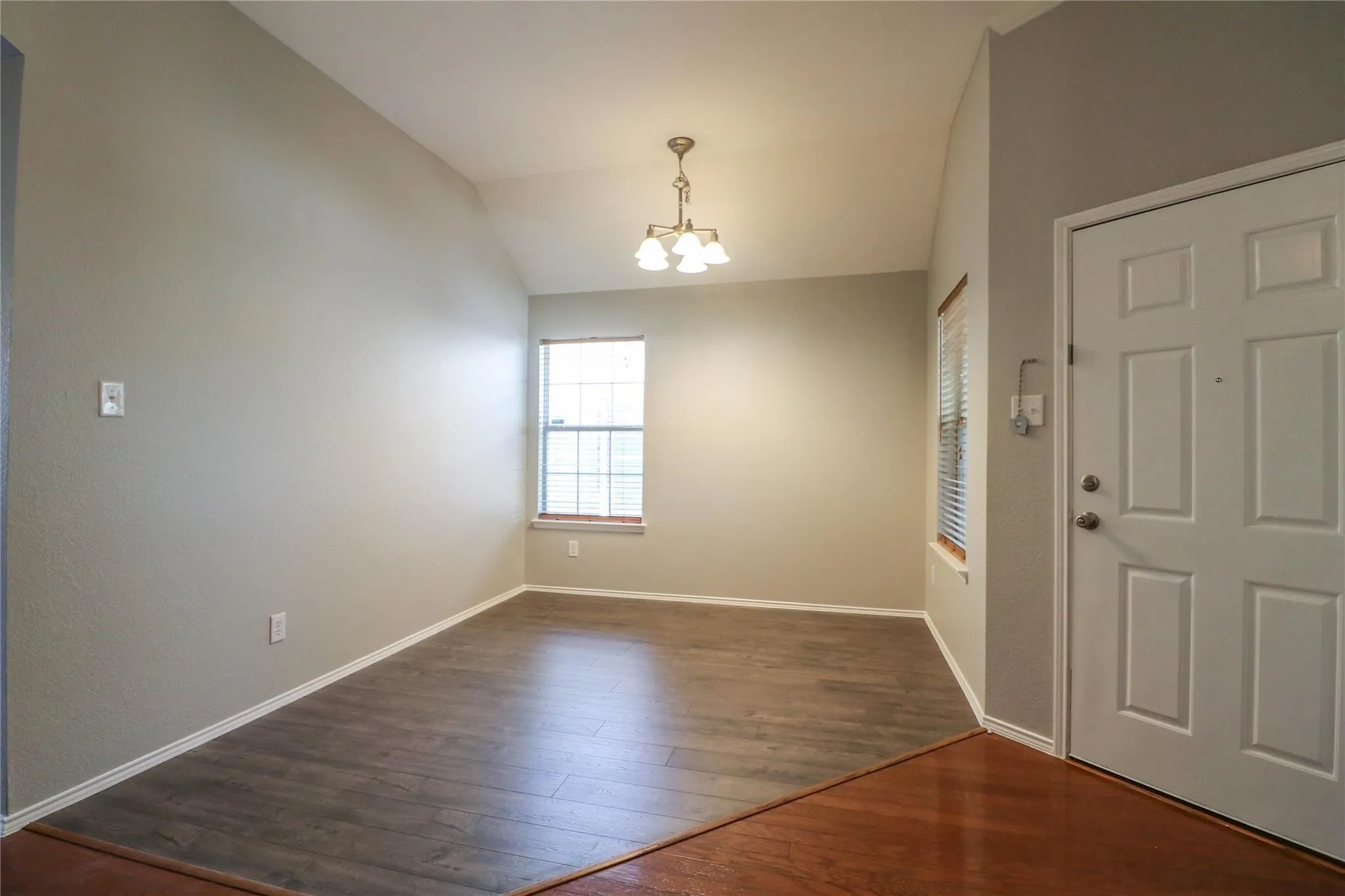 Vaulted ceiling, recessed window, chandelier, wood-finish flooring, paneled entry door