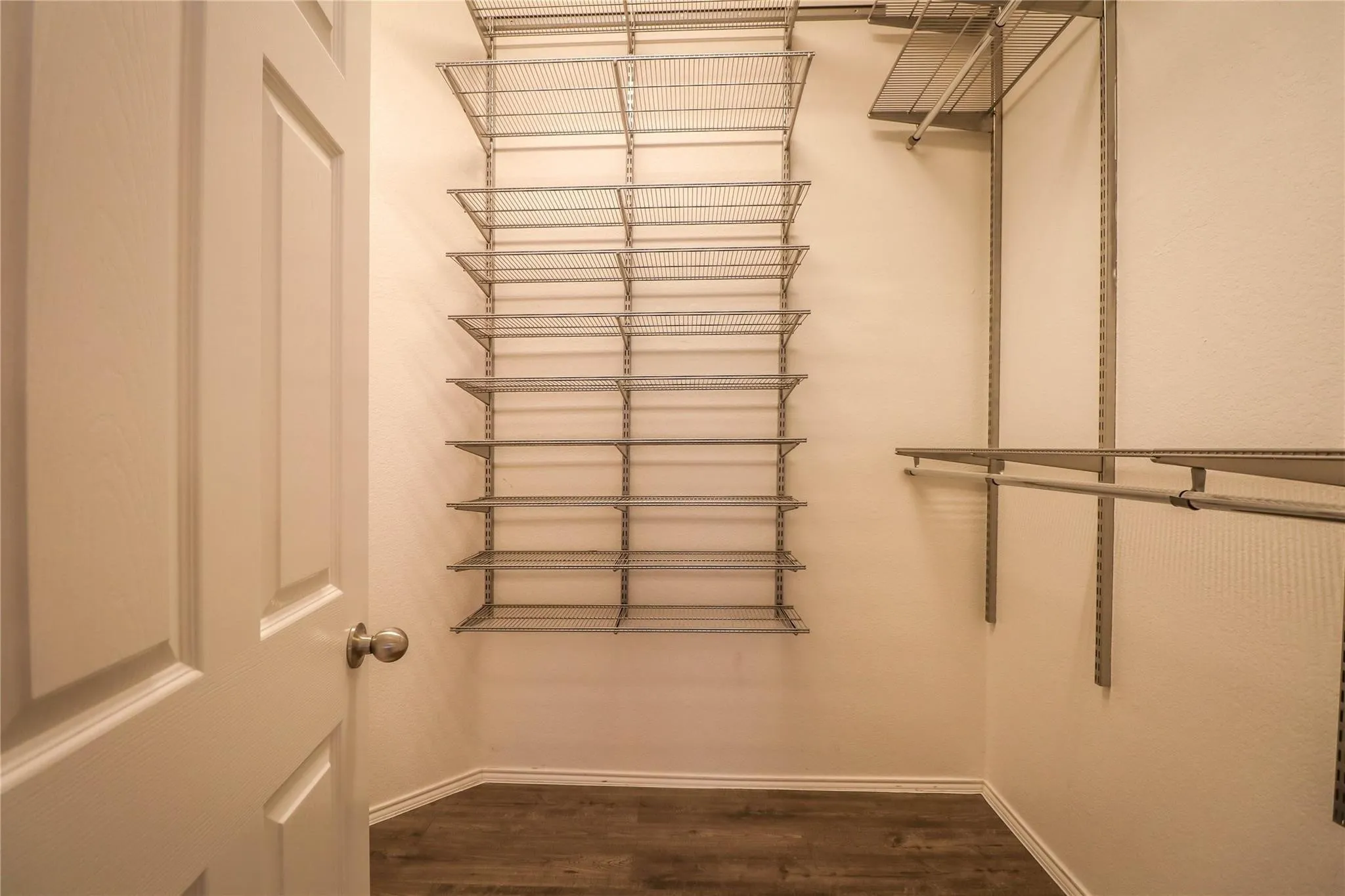 Walk-in closet featuring wire shelving, hanging rods, and wood-finish flooring