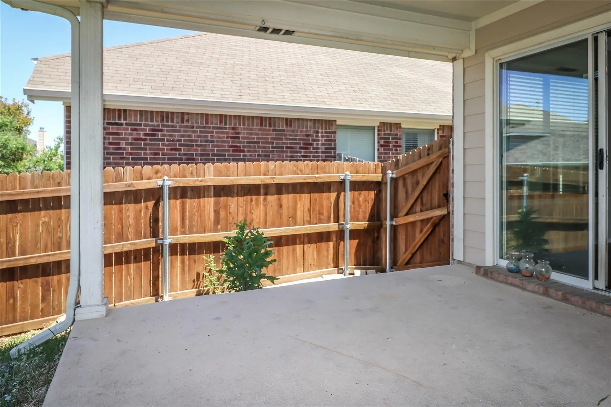 Covered patio featuring a concrete surface, wood fencing, and a full-light sliding glass door