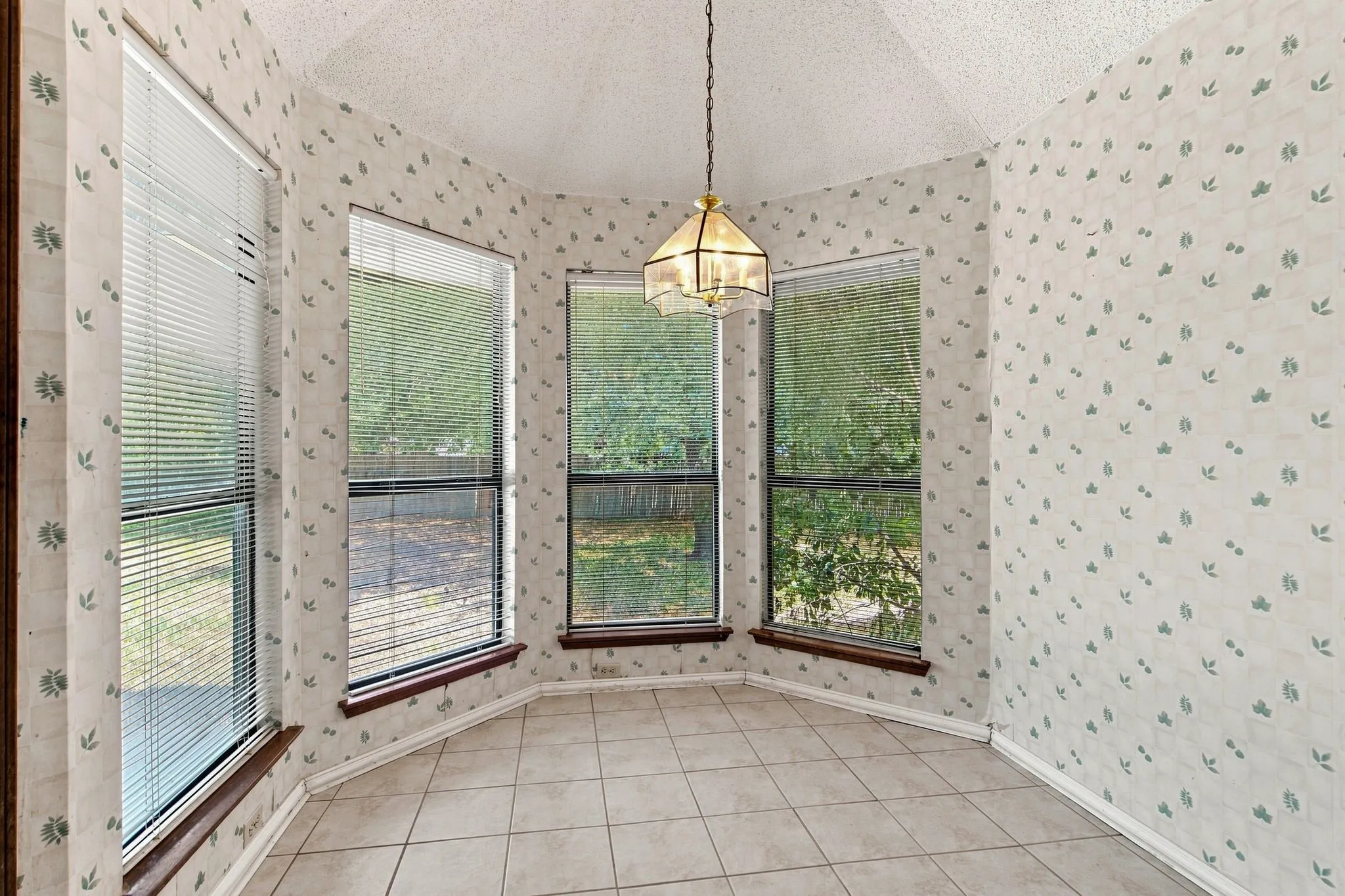 Bay window with three pane windows, tiled flooring, vaulted ceiling, and an overhead light fixture